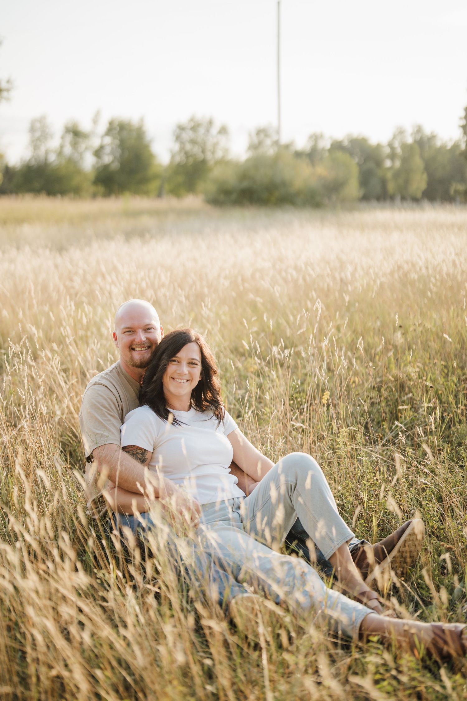 A couple relaxes together in a golden wheat field on a sunny afternoon.