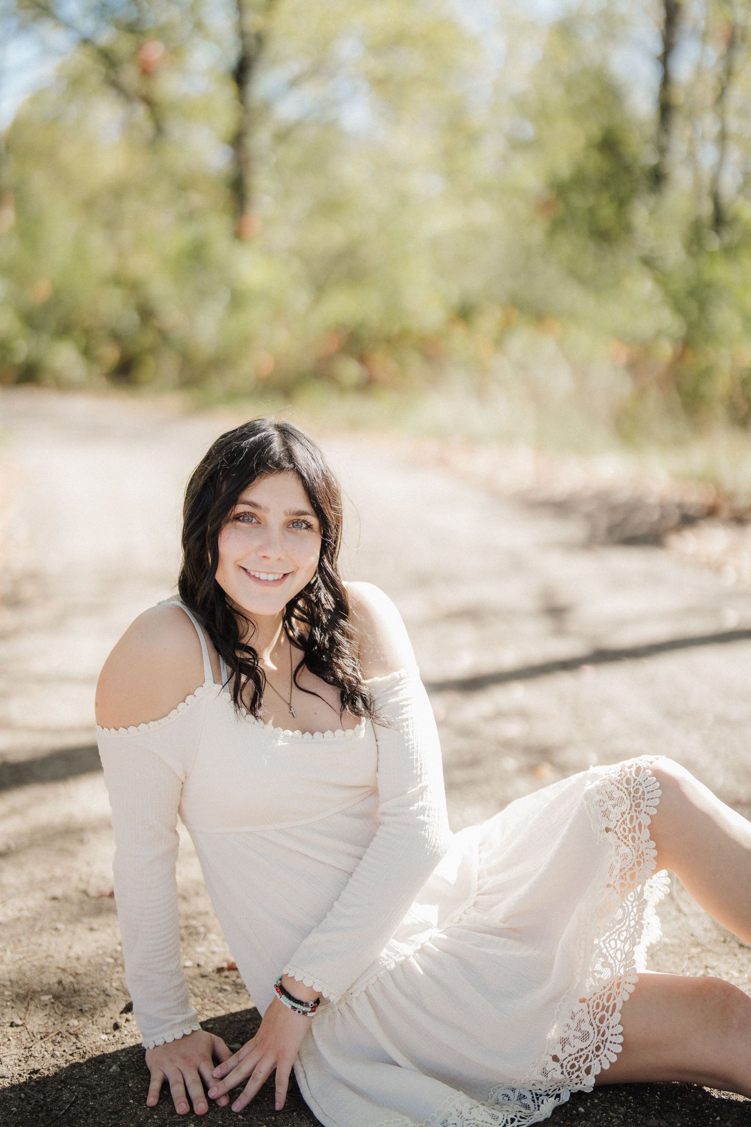 Dreamy outdoor portrait featuring a white lace dress against a sun-drenched natural backdrop.