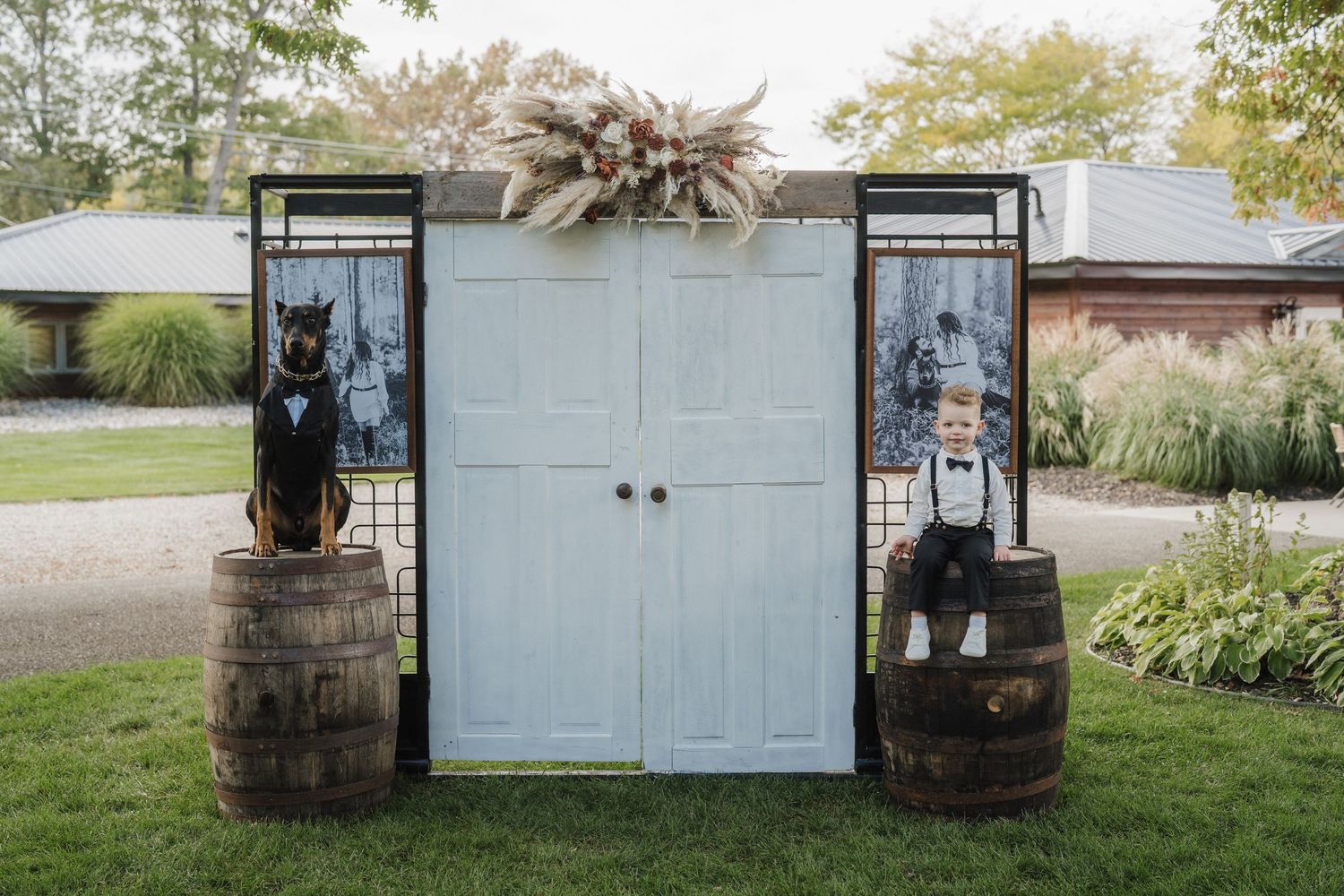 Rustic white barn doors with whiskey barrels and lanterns create a charming outdoor wedding backdrop.