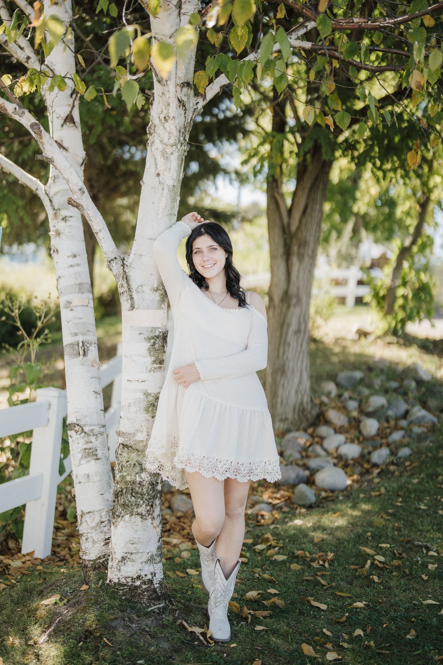 A serene outdoor photoshoot among white birch trees with dappled sunlight filtering through green leaves.