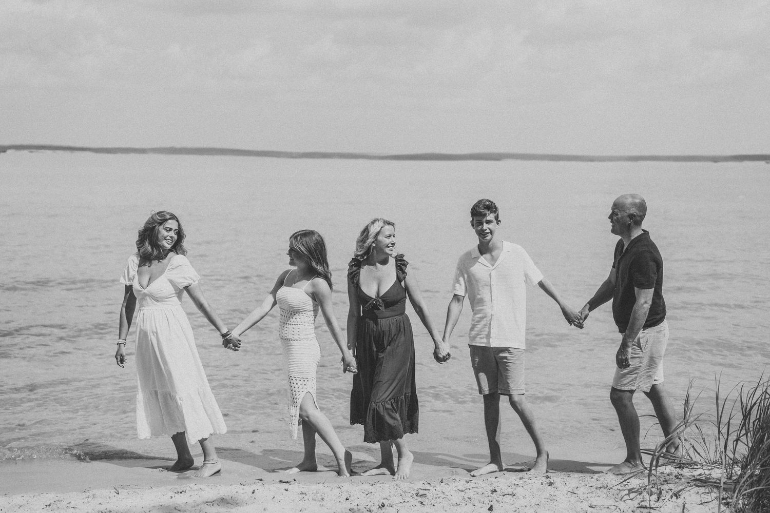 A series of black and white photos showing a group walking along a beach shoreline in formal attire.