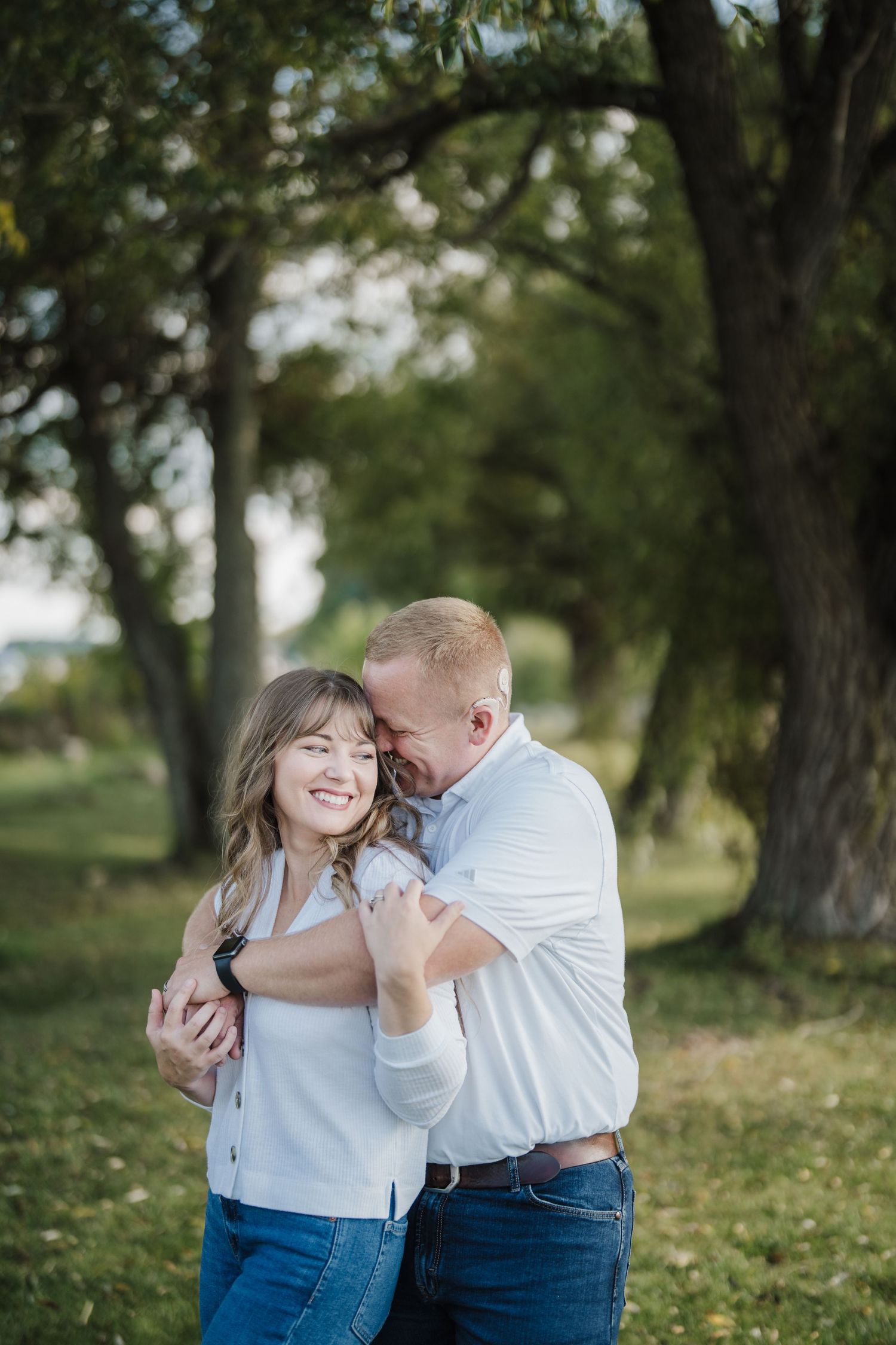 A romantic couple in blue jeans and white shirts share intimate moments while dancing together in a park setting.