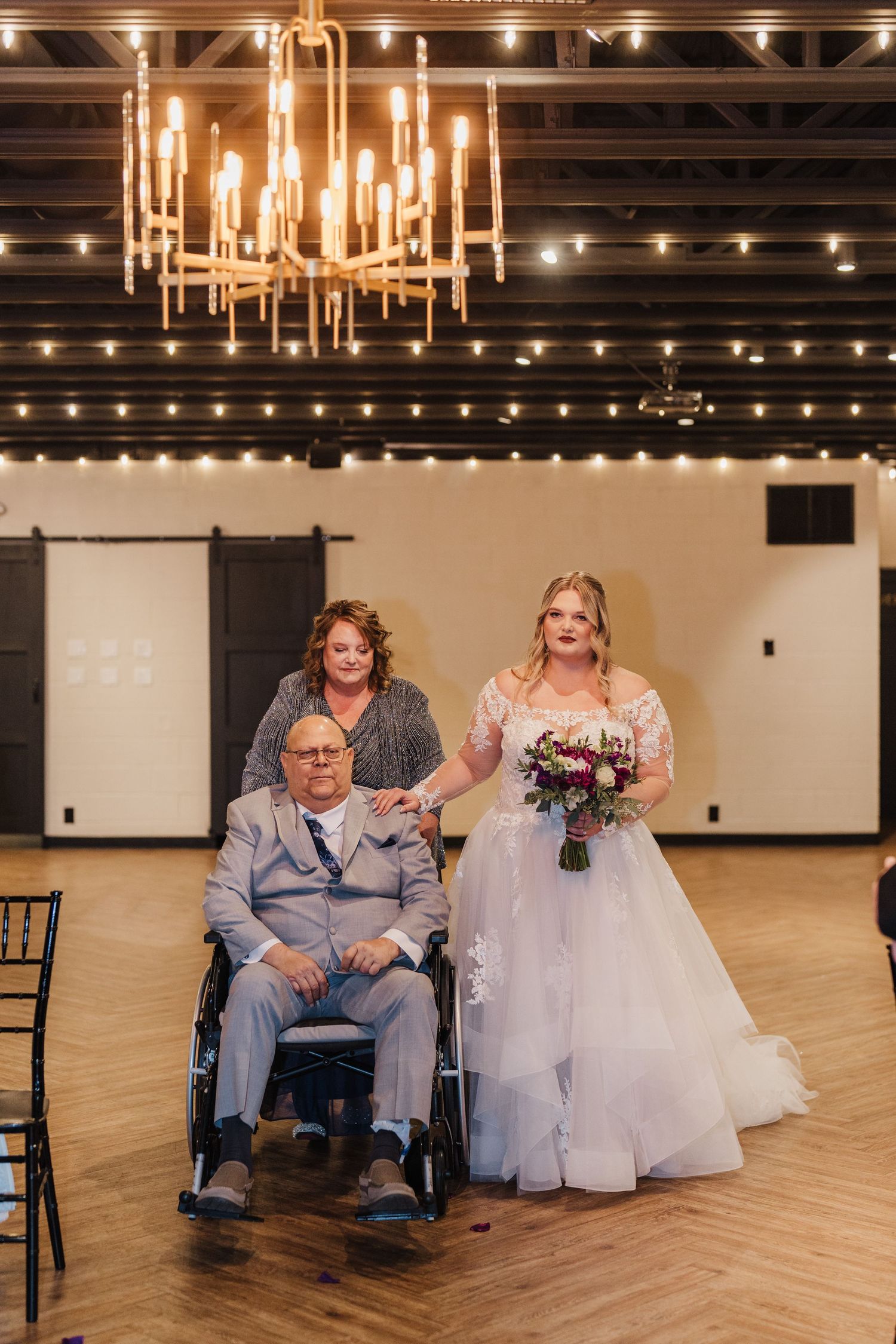 Wedding ceremony in an elegant venue with chandelier lighting and white brick walls.