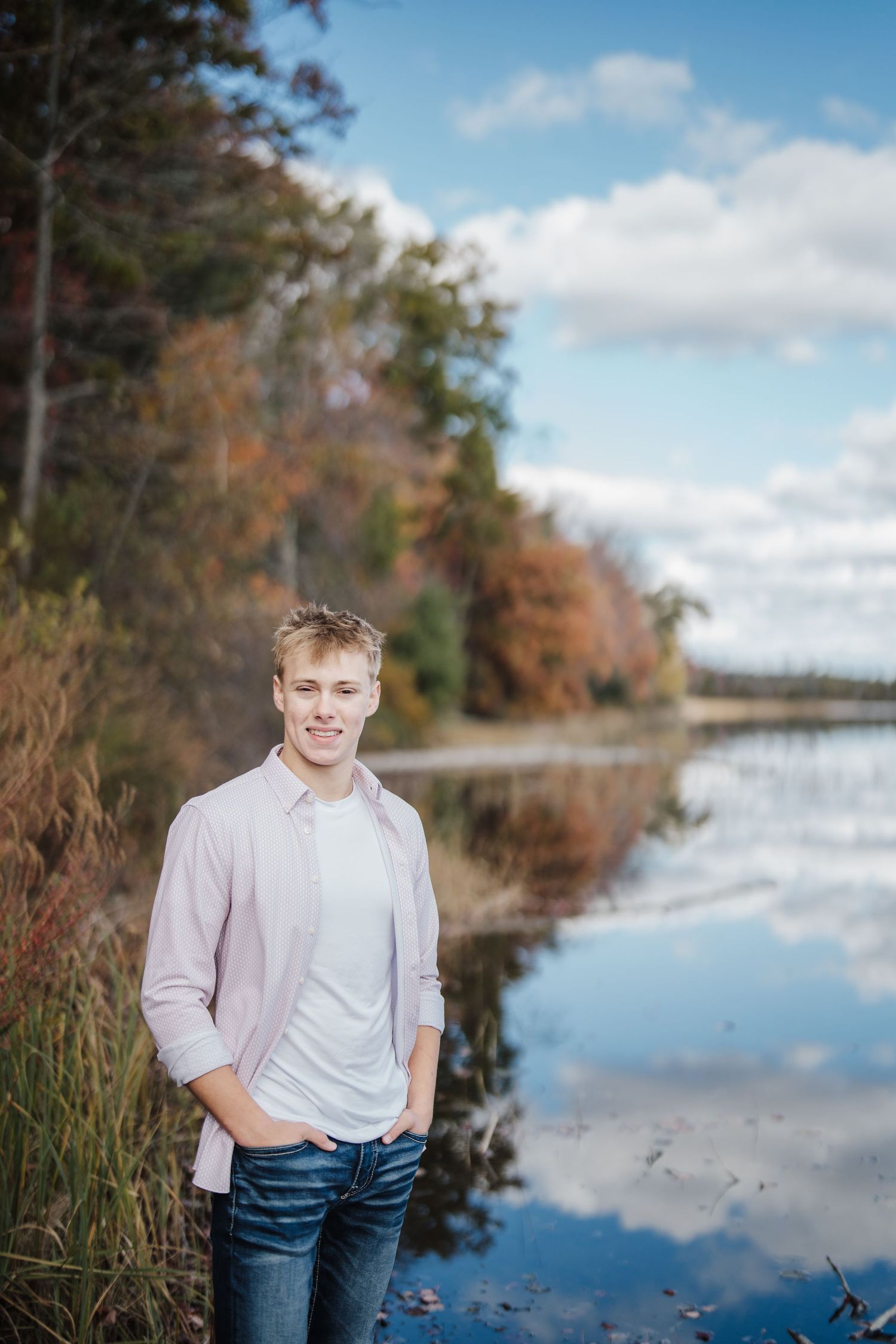Scenic waterfront portraits with fall foliage and reflective water in the background on a sunny day.