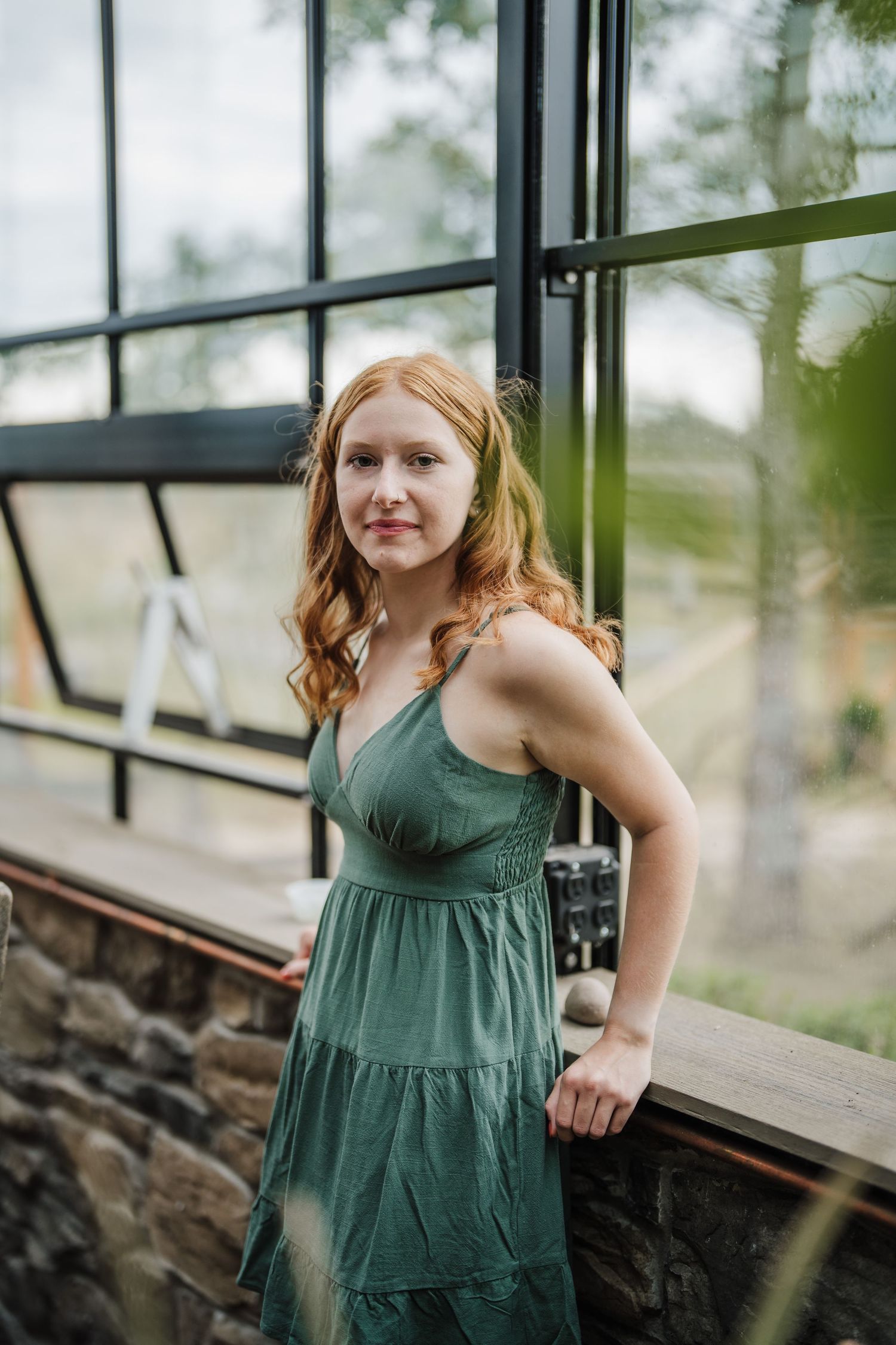 A green summer dress is showcased against a modern interior with large windows and stone walls.