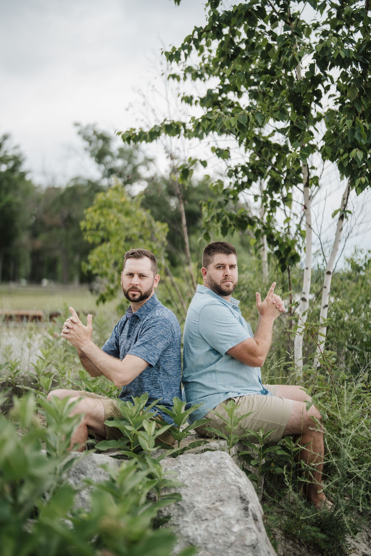 Two people relaxing on large rocks surrounded by greenery and trees.