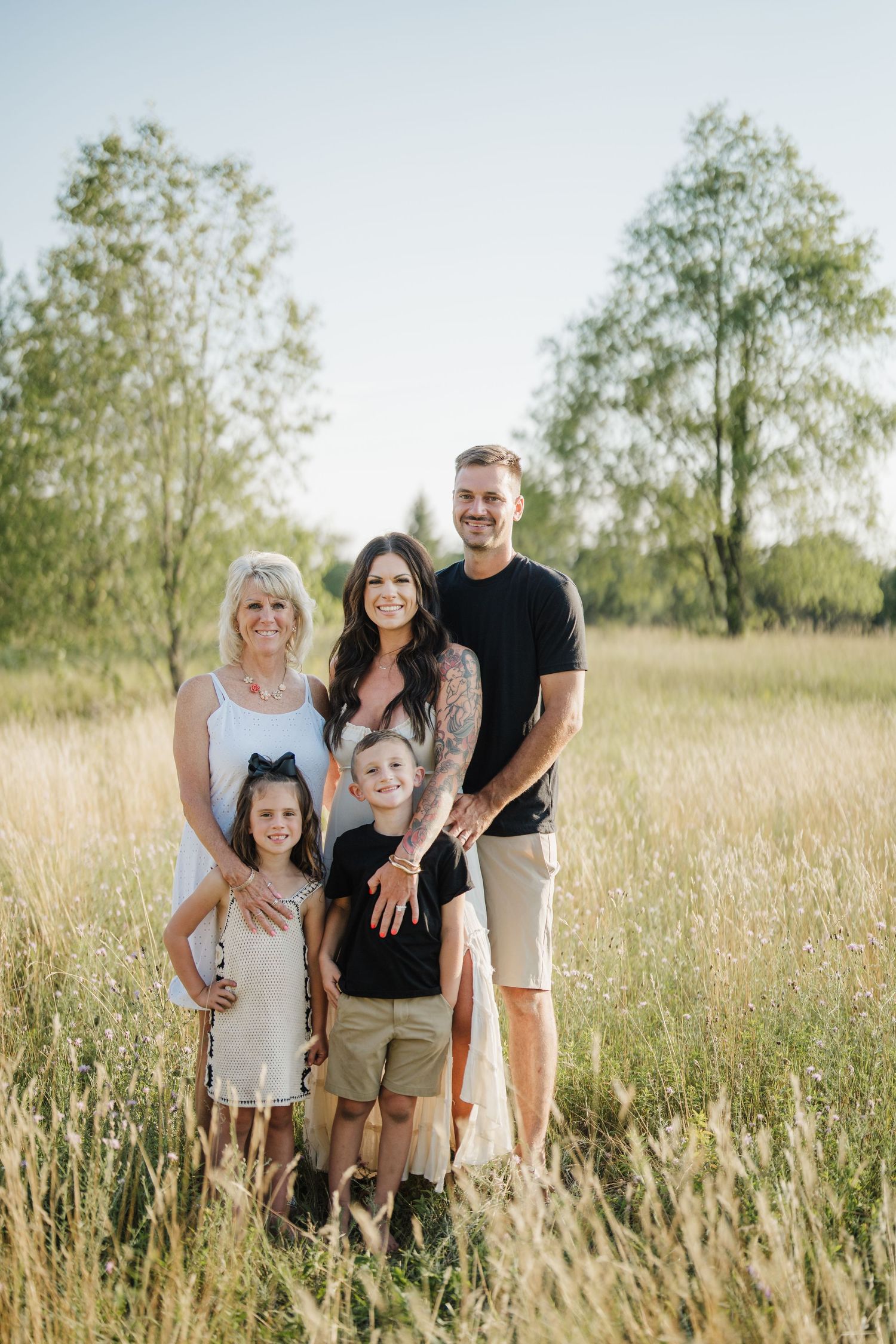 Family enjoying a sunny afternoon together in a tall grass field during golden hour.