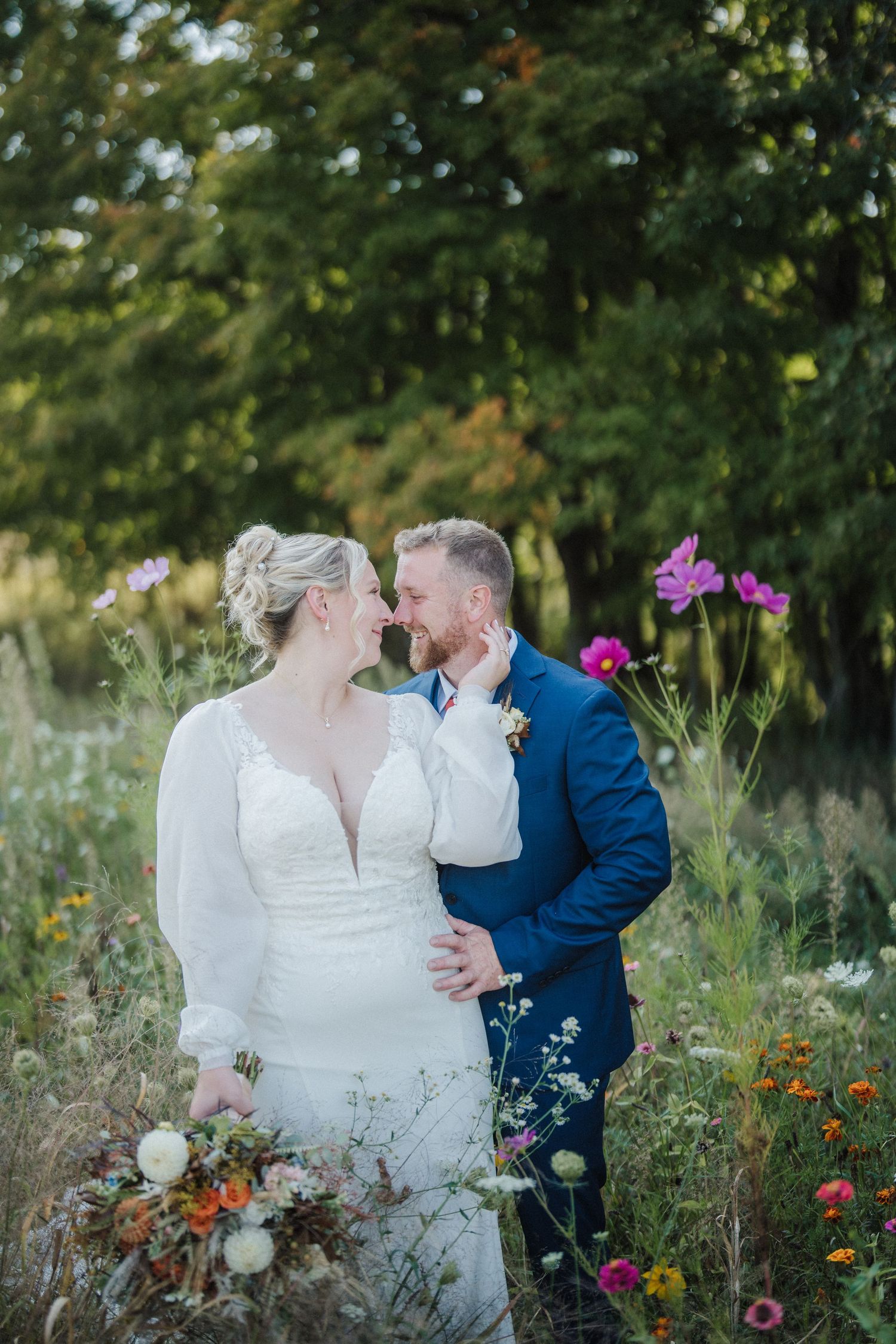 A romantic wedding couple shares an intimate kiss among vibrant wildflowers in a natural garden setting.