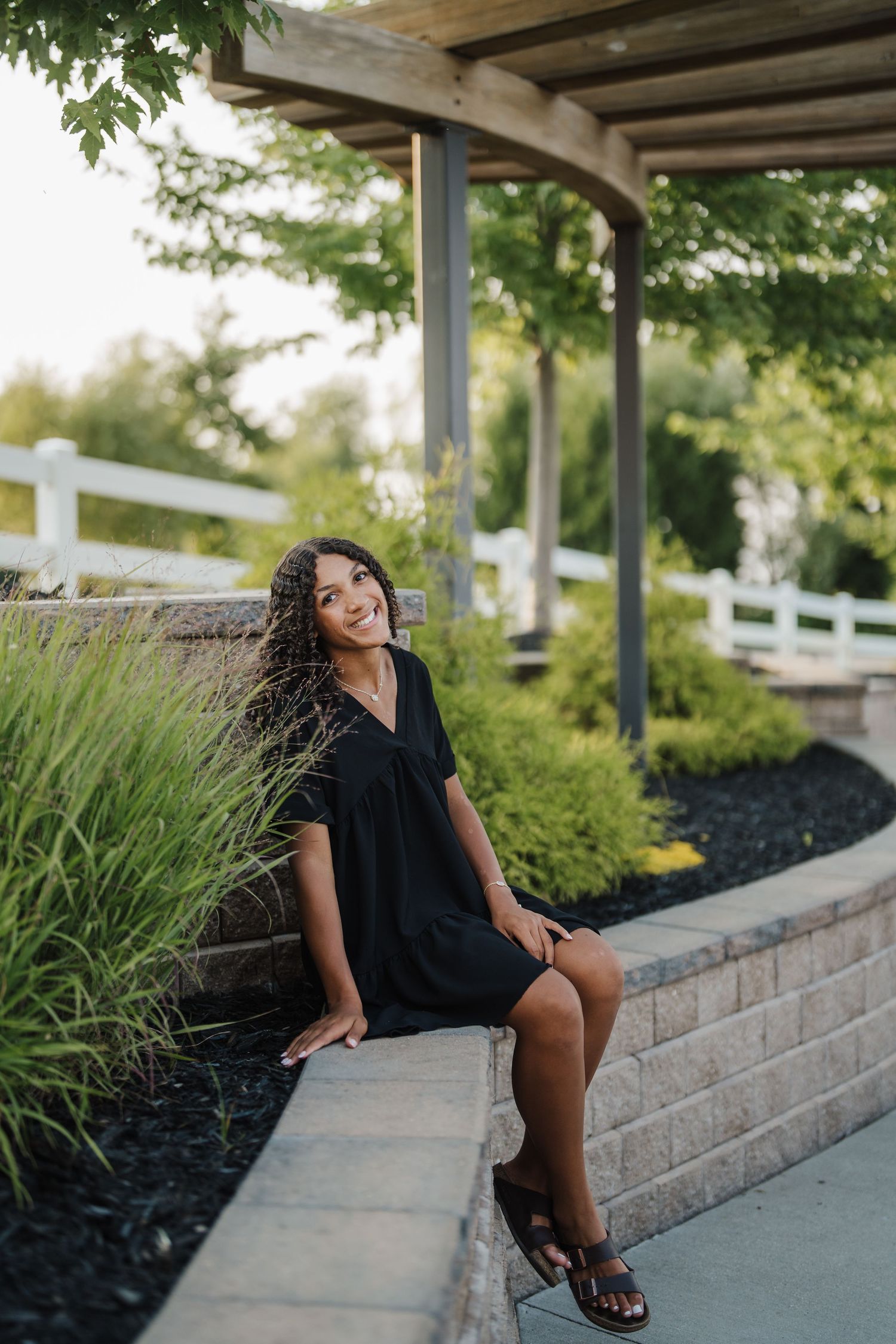 Casual portraits on stone steps with landscaping and wooden pergola in background.