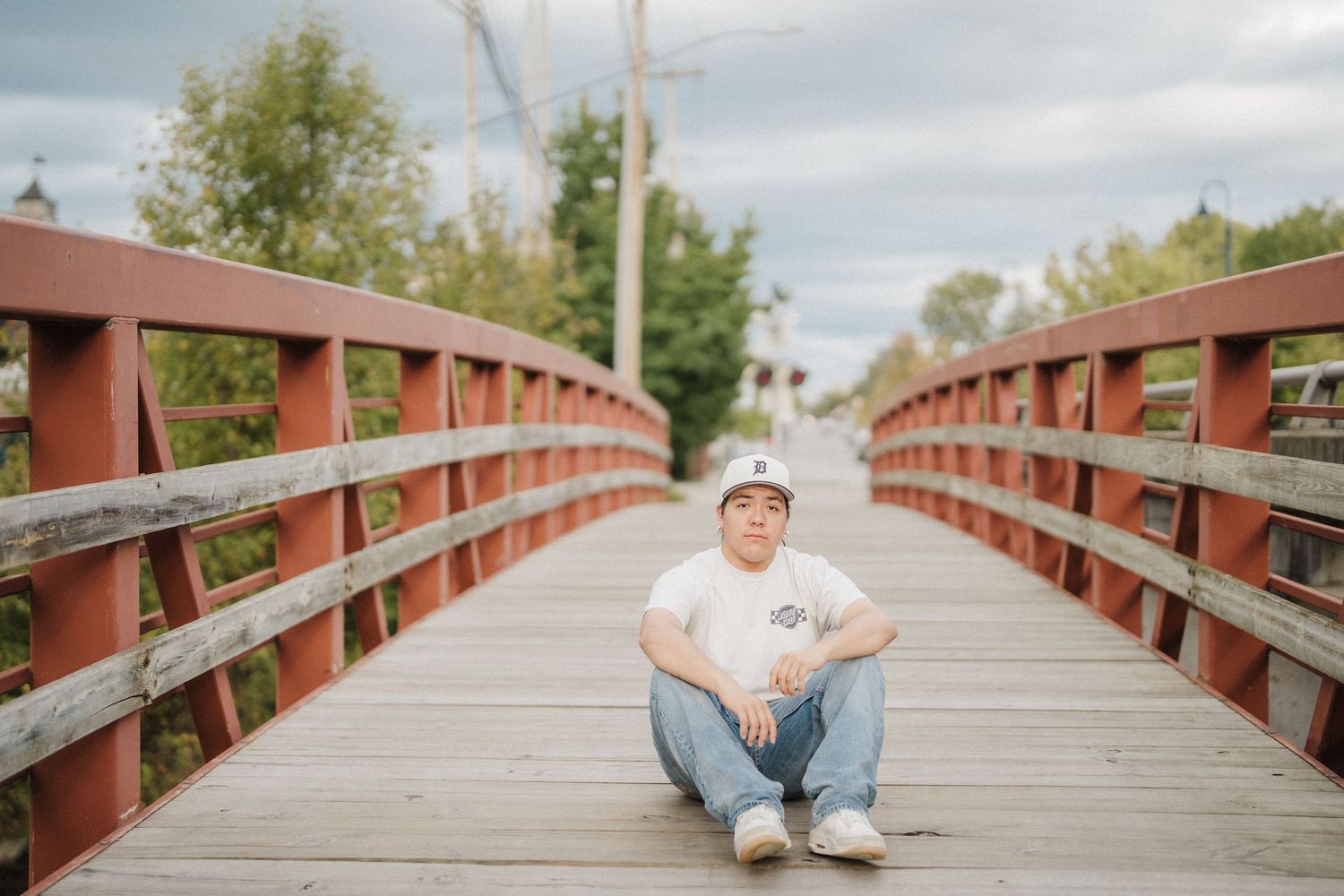 A series of connected photos showing someone sitting and posing on a wooden bridge walkway in a natural setting.
