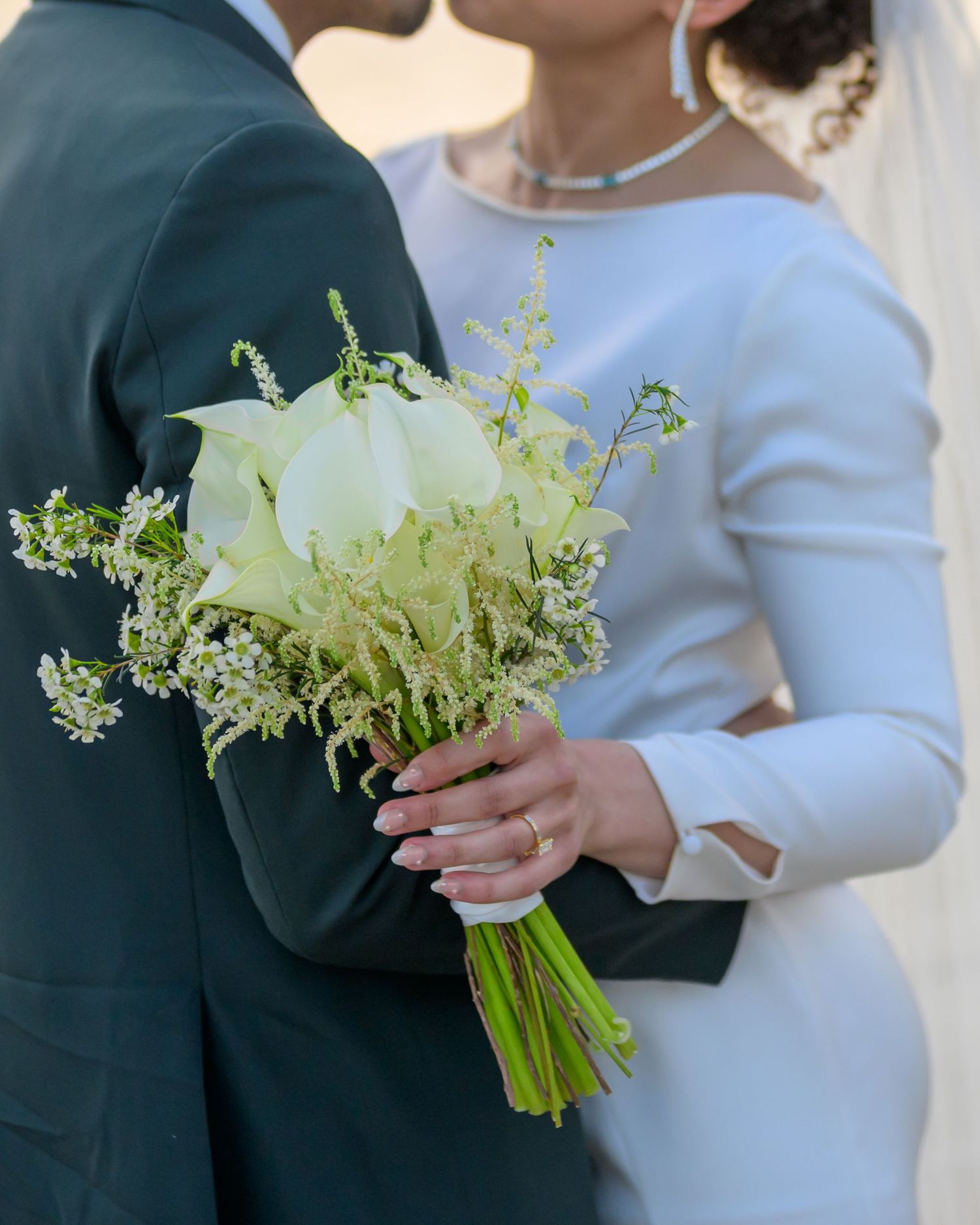 Close-up of elegant white floral bouquet held against formal attire.