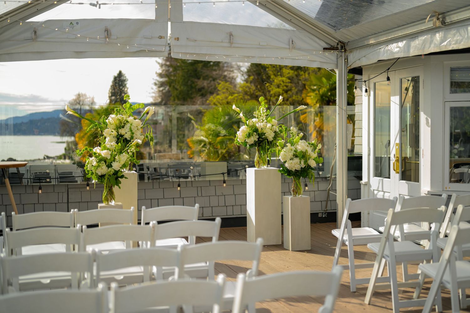 White chairs set up for outdoor wedding ceremony under covered venue with mountain views.