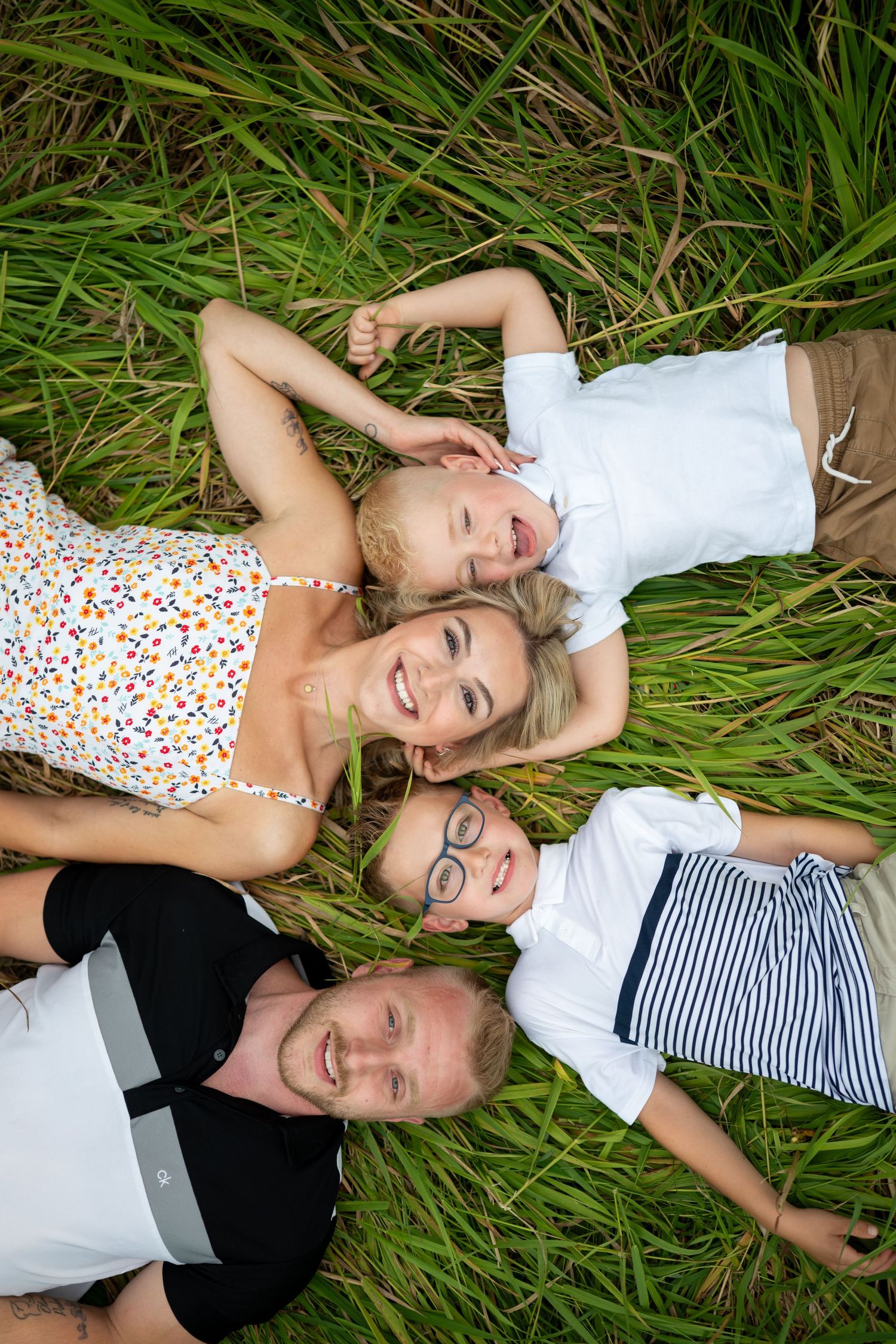 People lying in green grass wearing casual summer outfits while enjoying a sunny day outdoors. Pitt Meadows