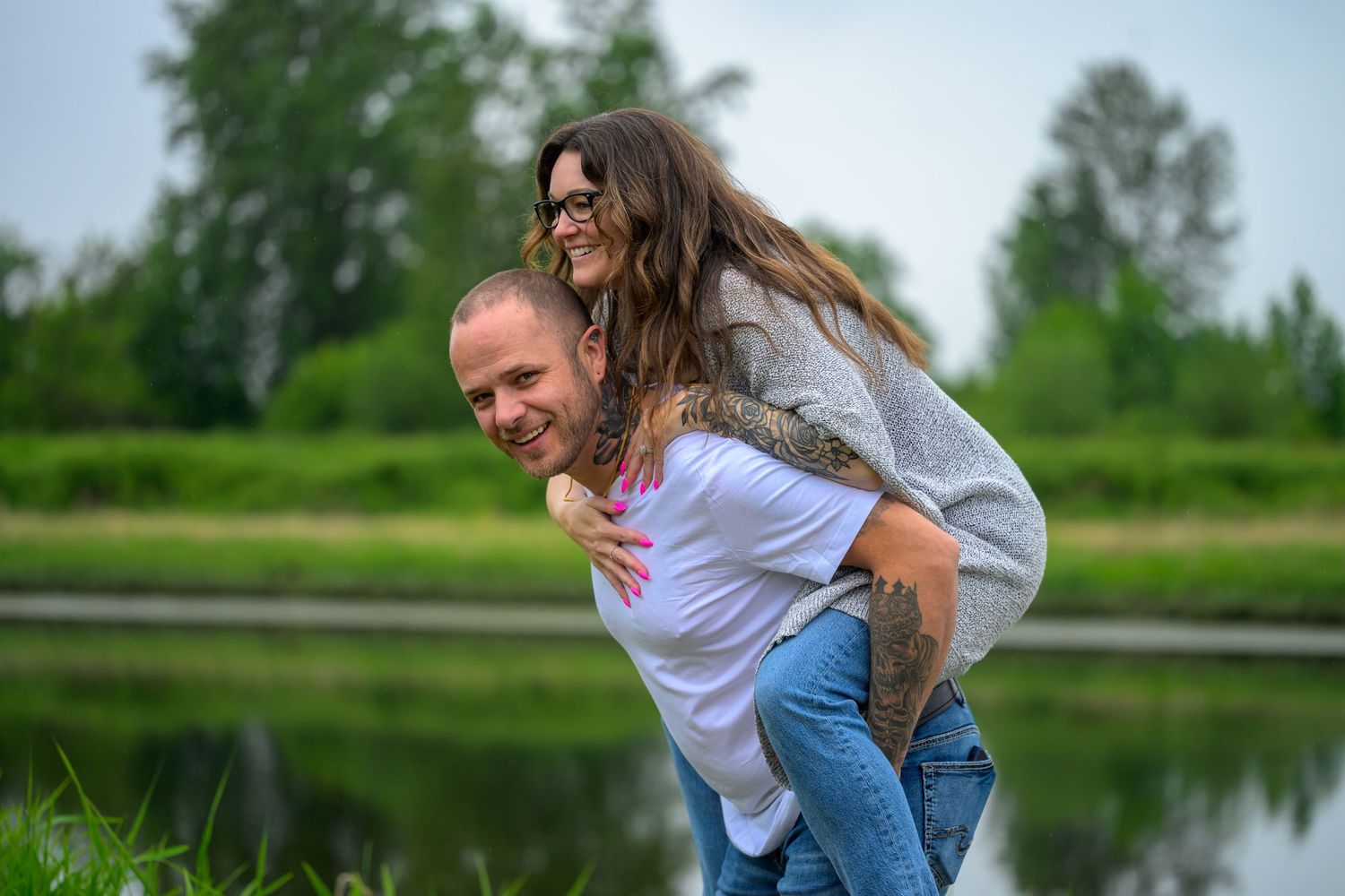 Couple enjoying romantic moments by a lake on a cloudy day.