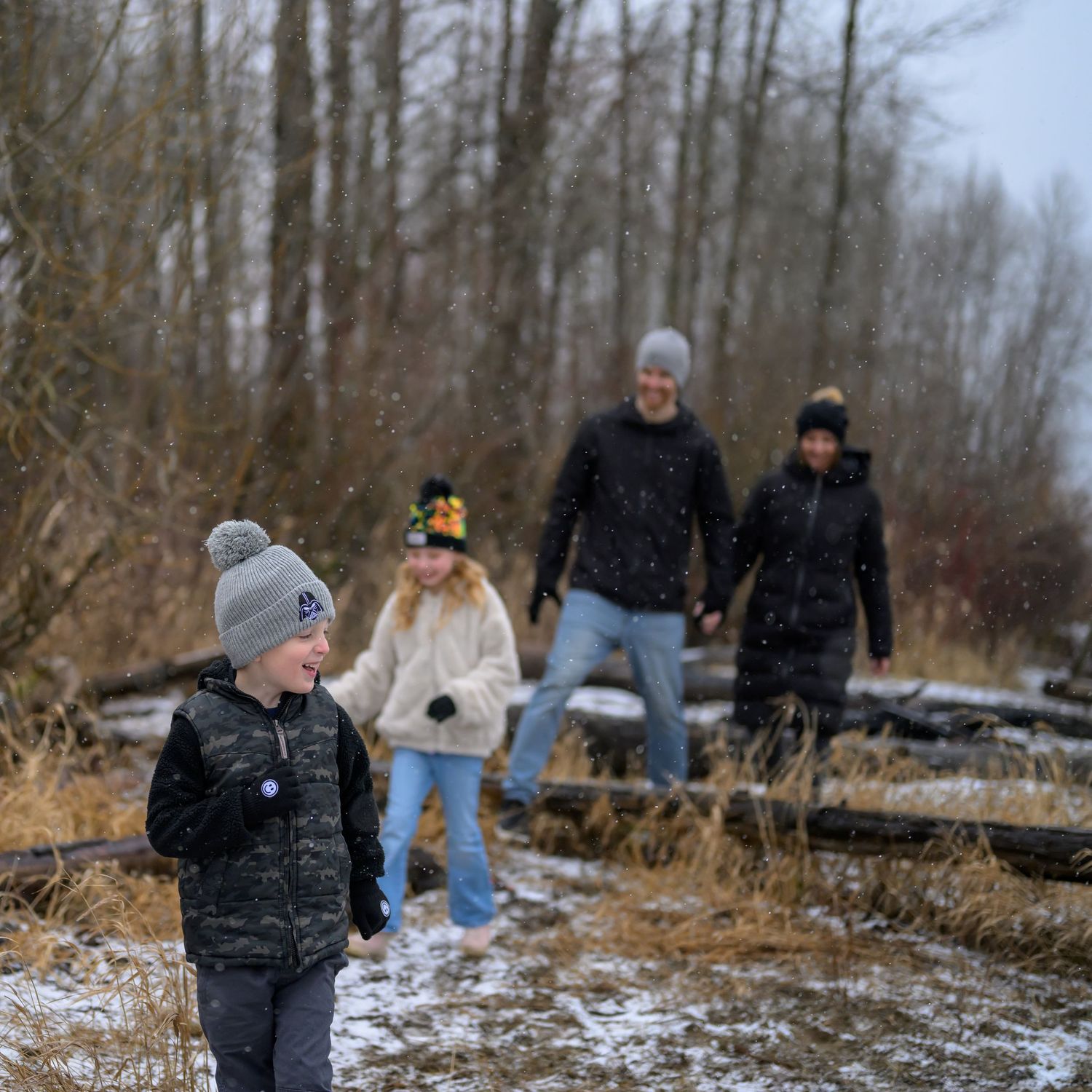 People enjoying a winter walk along a snowy riverbank in Port Coquitlam