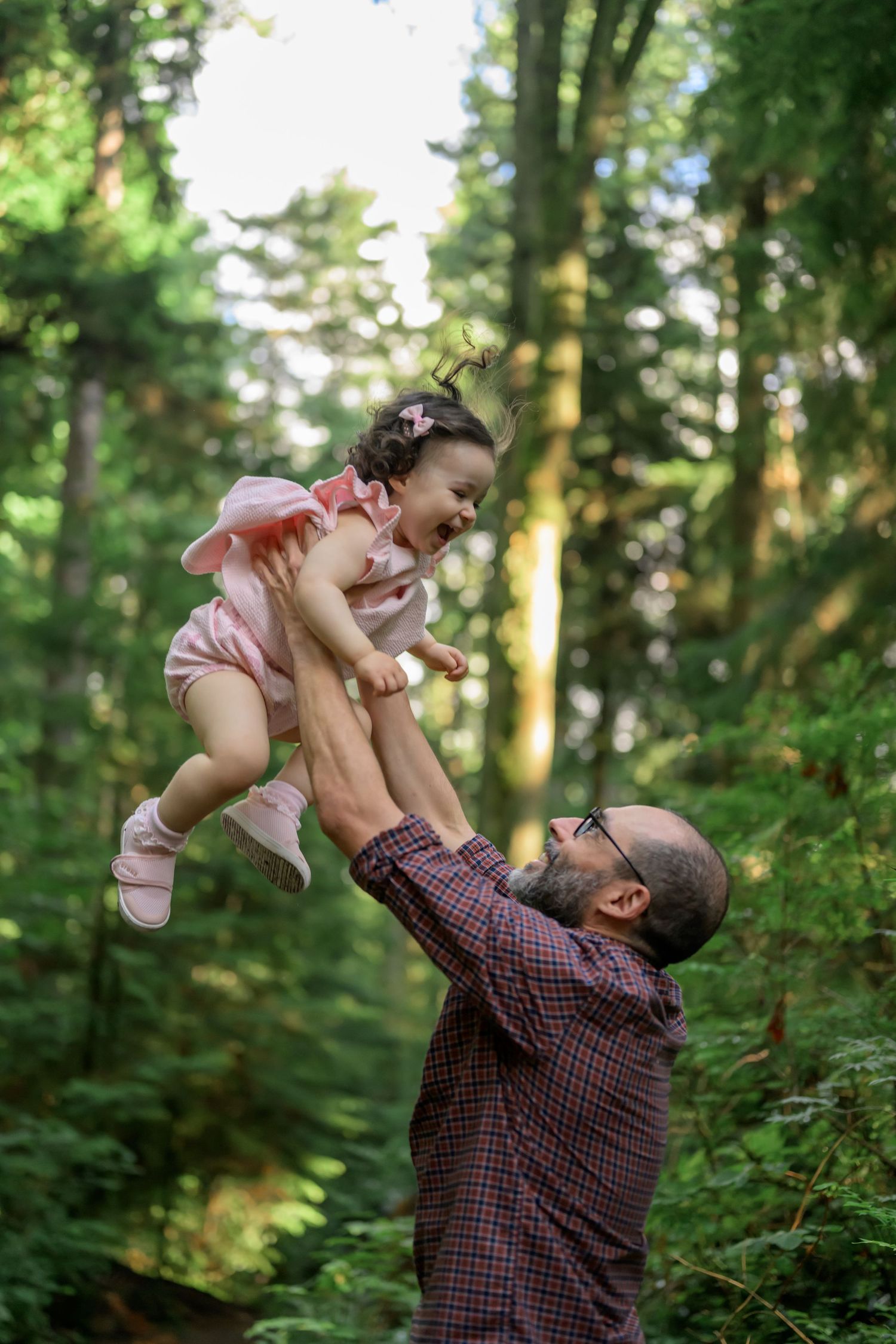 Playful moments captured in a lush green forest setting with warm sunlight filtering through the trees.