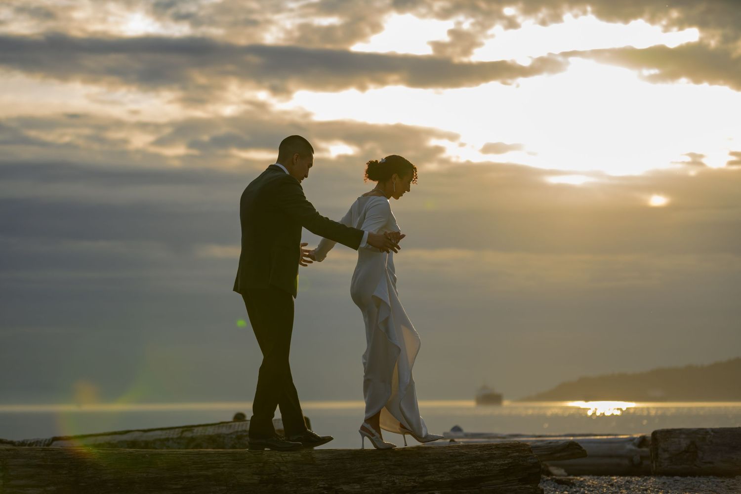 Couple silhouetted against a stunning ocean sunset, sharing a romantic moment on a beach at golden hour.