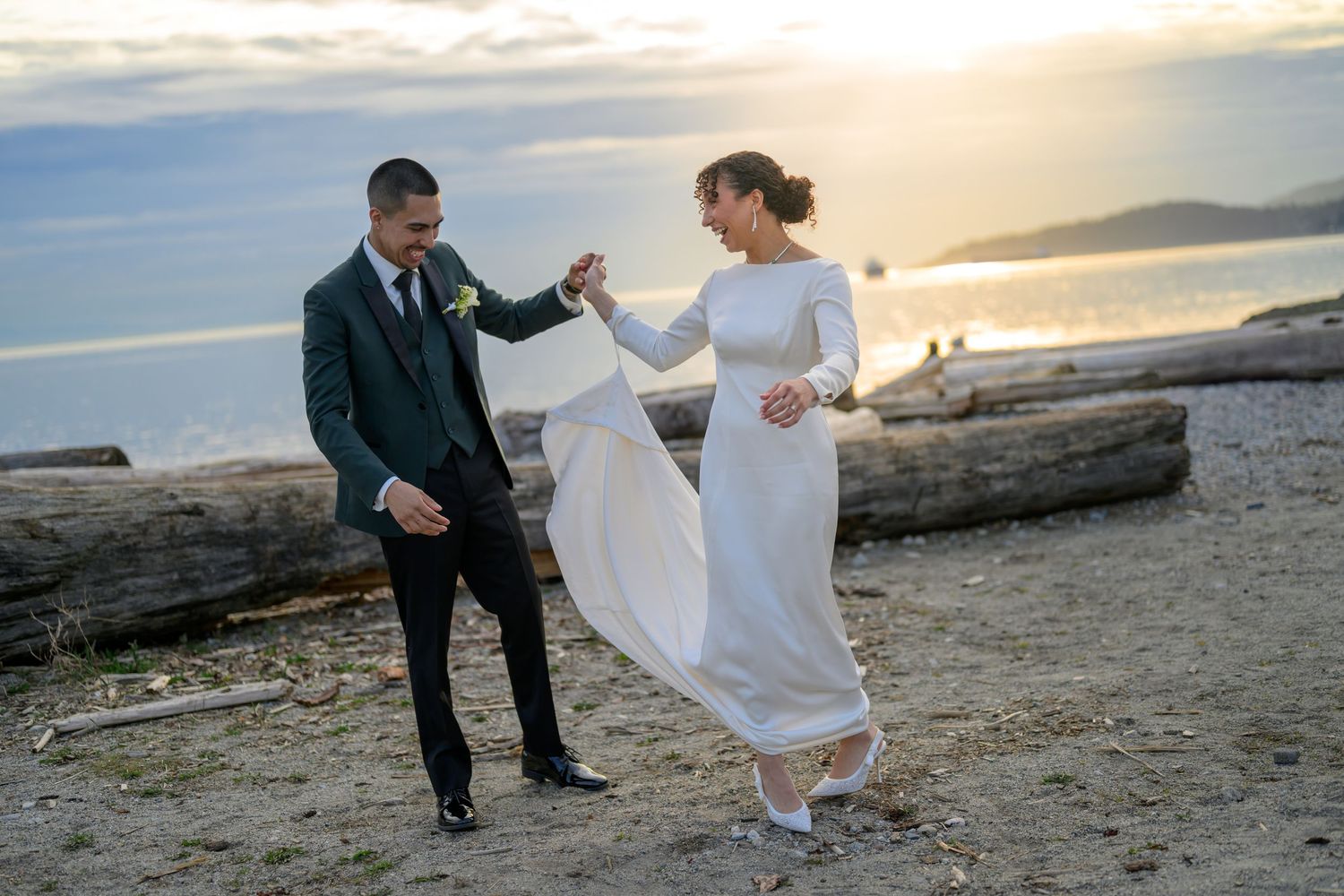Newlyweds dance together on a scenic beach at golden hour.