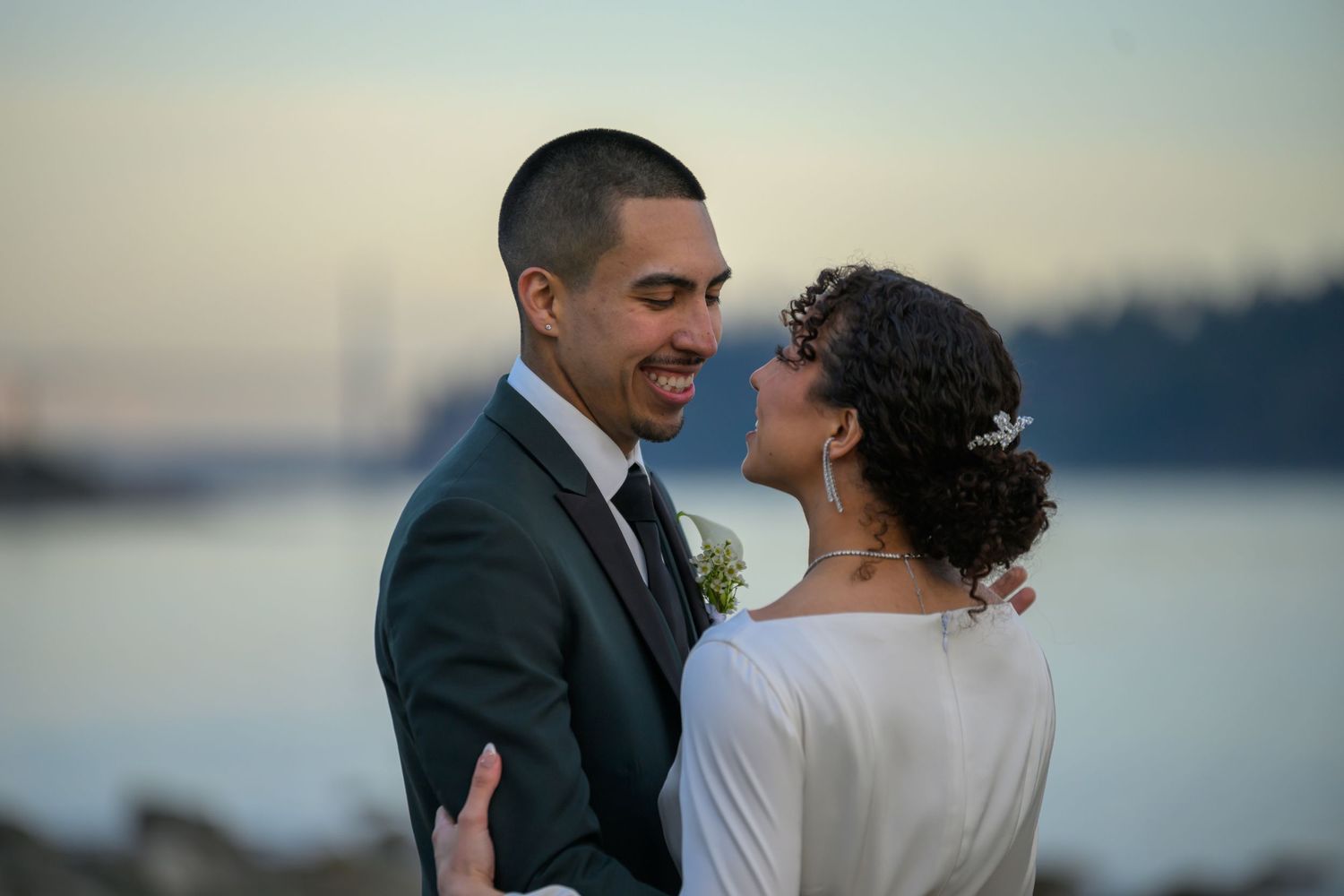 Couple sharing intimate moment at waterfront during sunset.