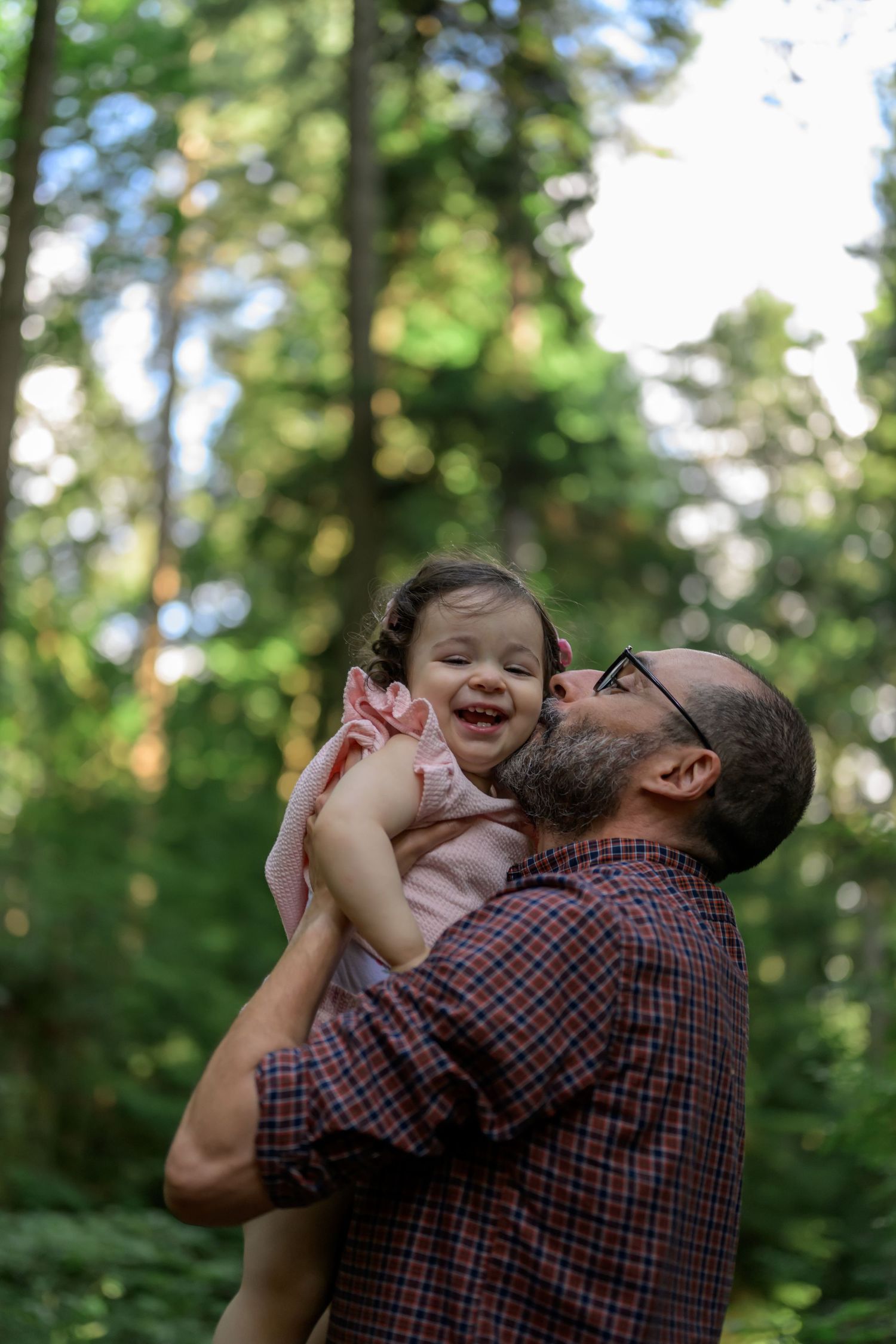 Playful moments between parent and child in wooded outdoor setting.