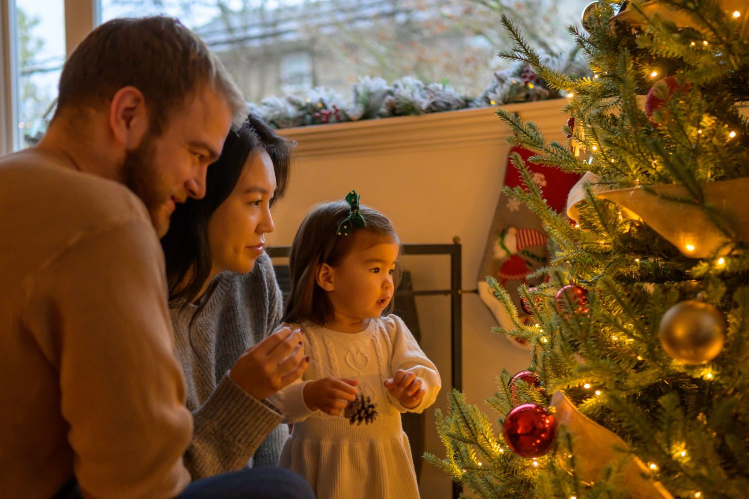 A family gathers around a beautifully decorated Christmas tree in a cozy living room during the holiday season.
