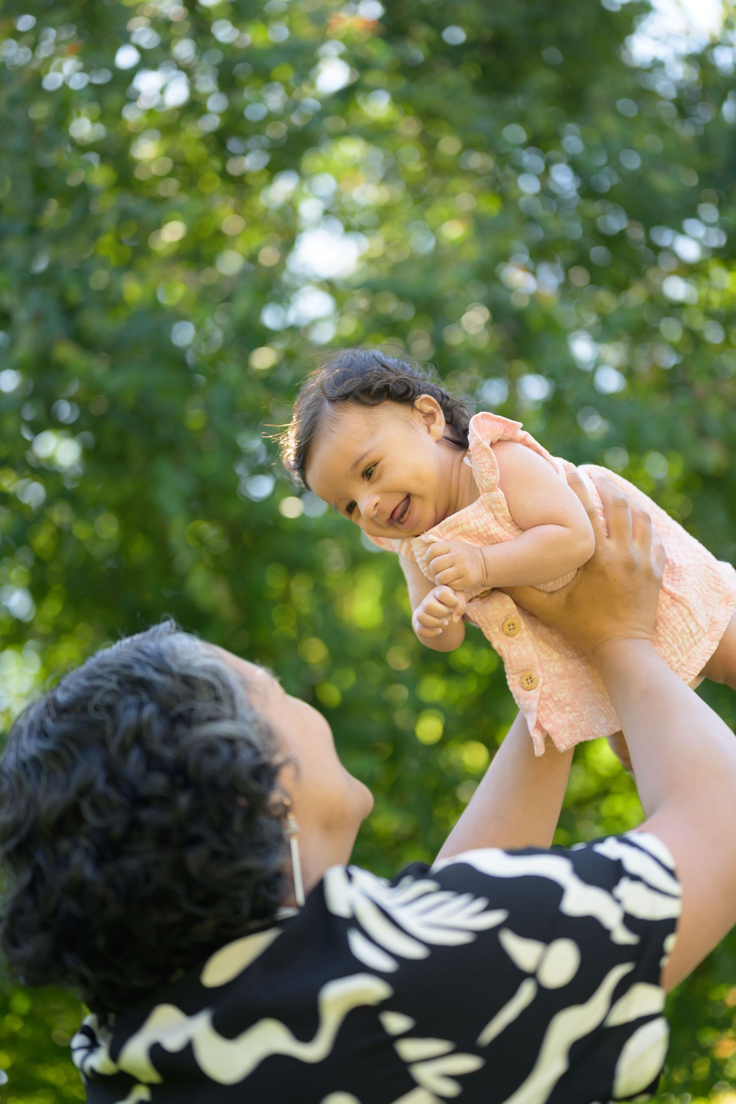 Joyful moments shared outdoors against a backdrop of sunlit green foliage.