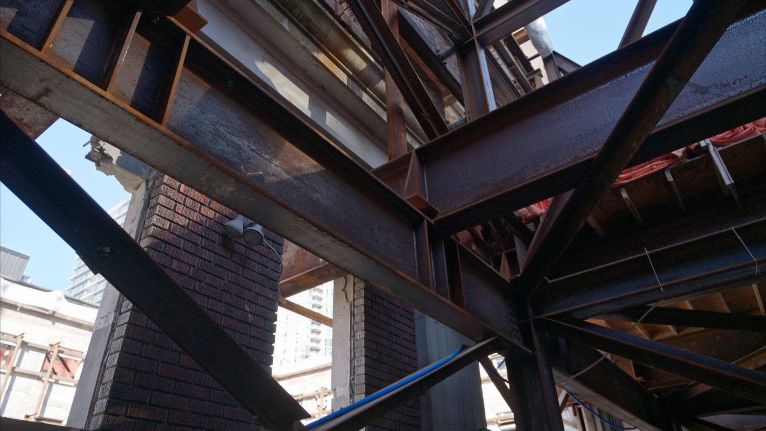 Interior view of building construction showing dark metal beams and structural supports.