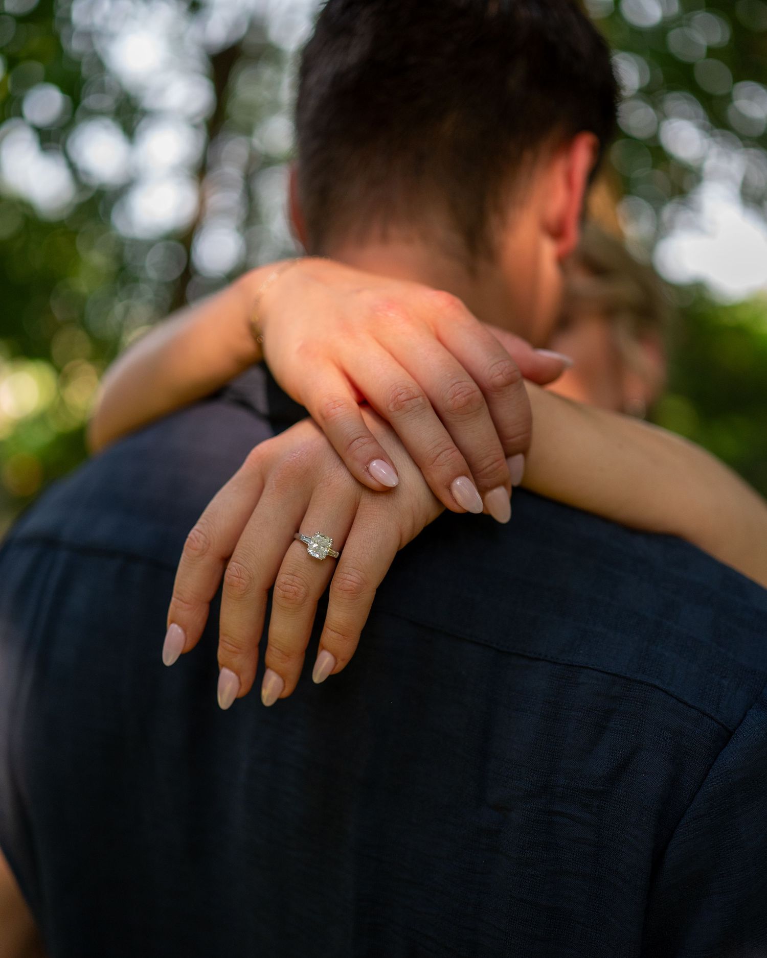 Close-up shots focusing on hands and a sparkling engagement ring against a dark shirt.