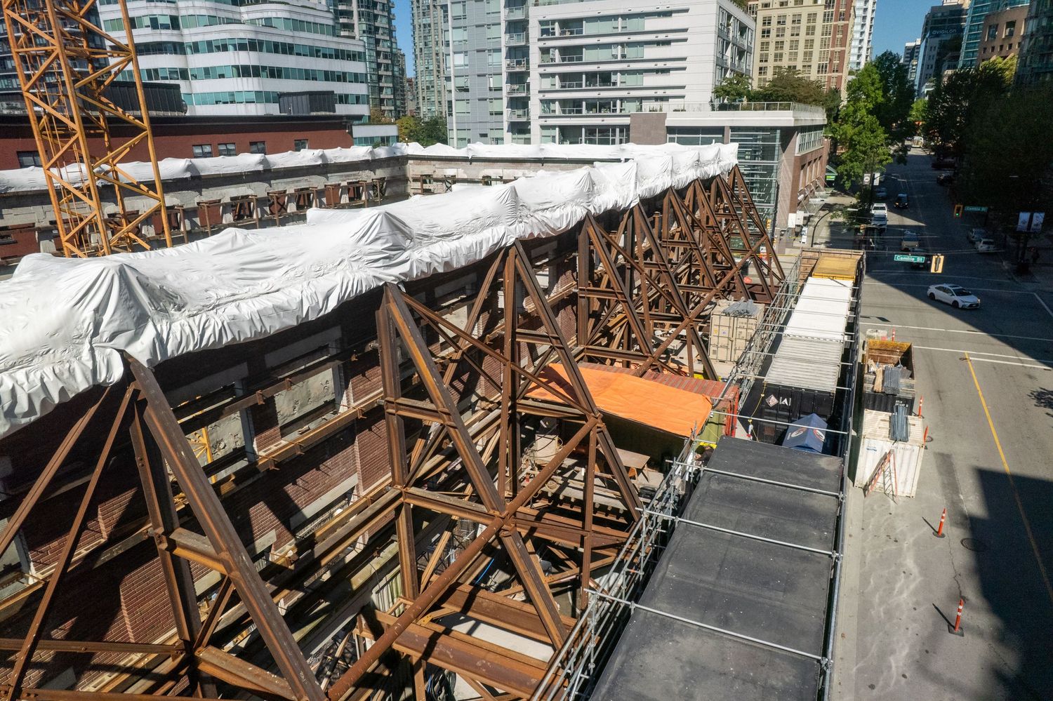 Construction site with steel beams and scaffolding against modern city buildings.
