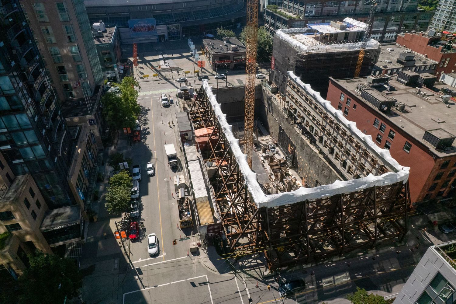 Aerial view of construction site with exposed structural framework and surrounding city buildings.