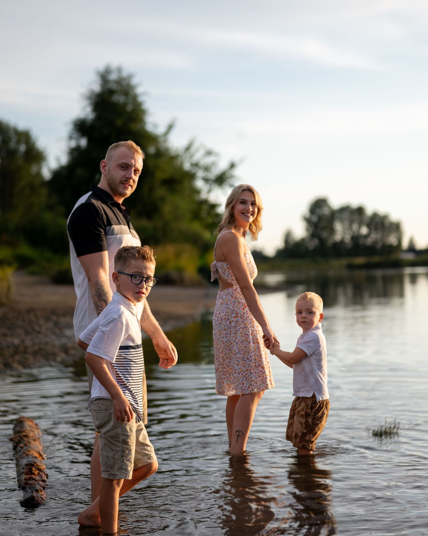 Family wading in shallow water during sunset by the lake.
