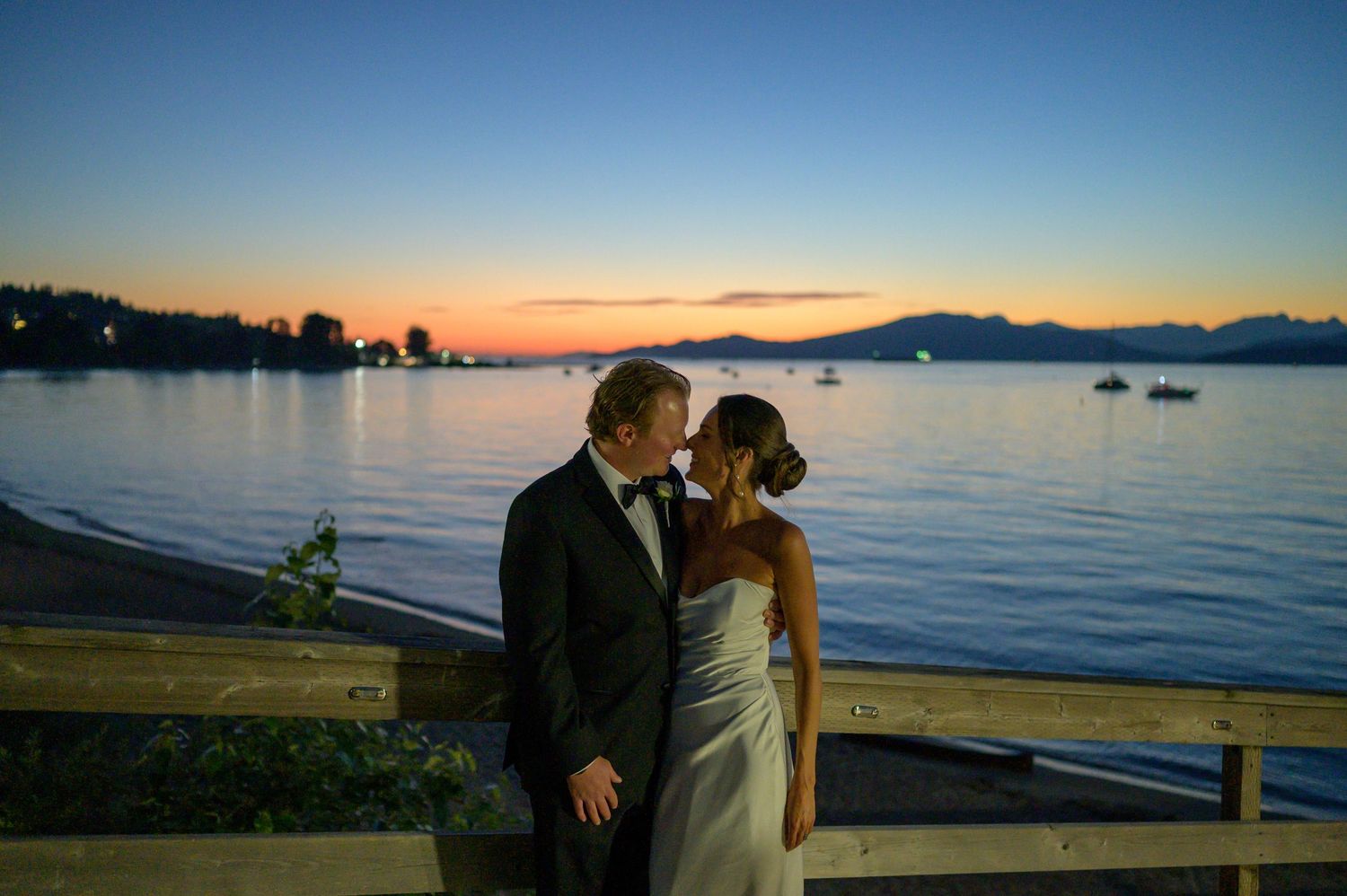 A romantic sunset beach photoshoot with mountains and water in the background.