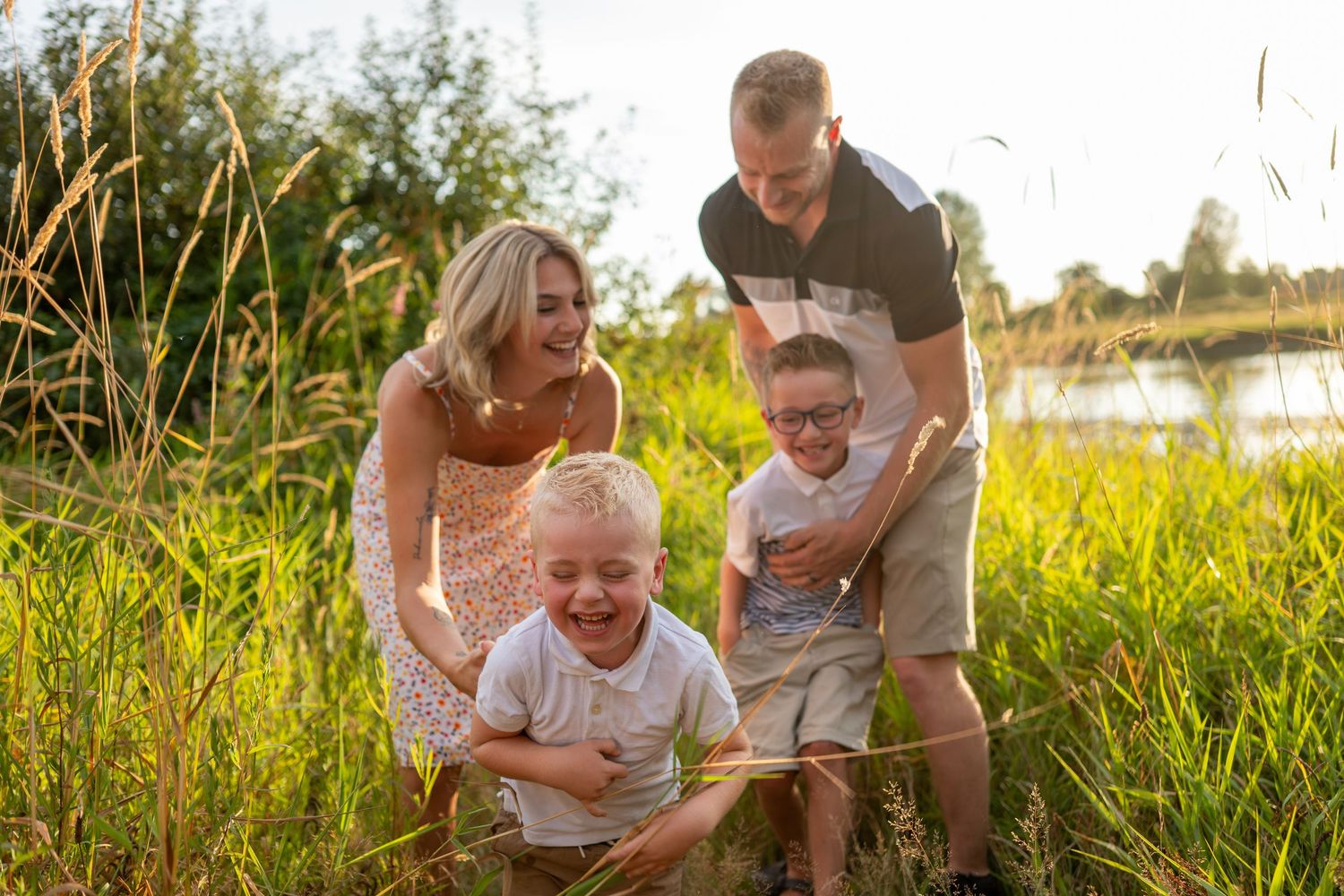 Joyful family playing together in tall grass during golden hour.