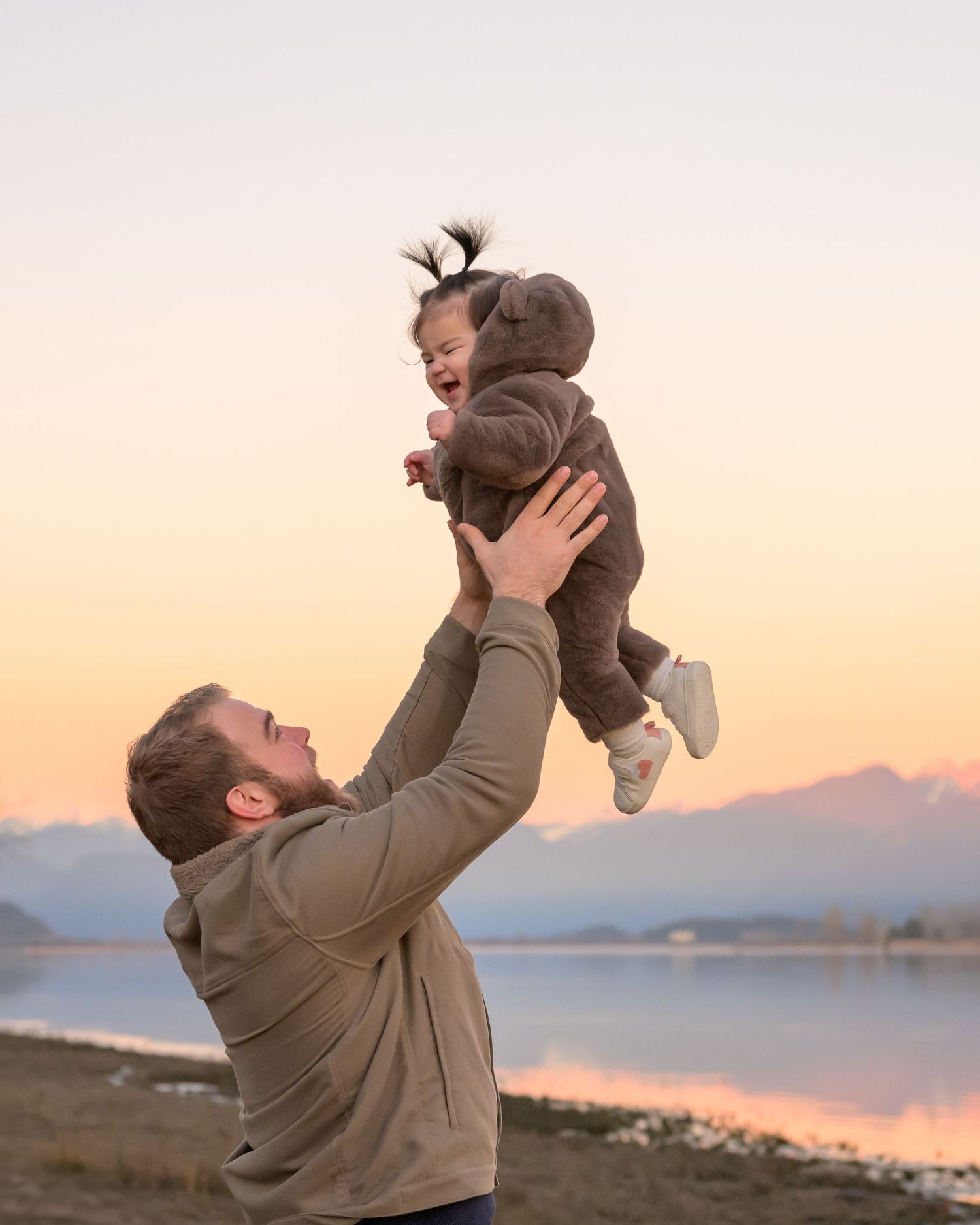 A playful moment captured at sunset with mountains and water in the background.