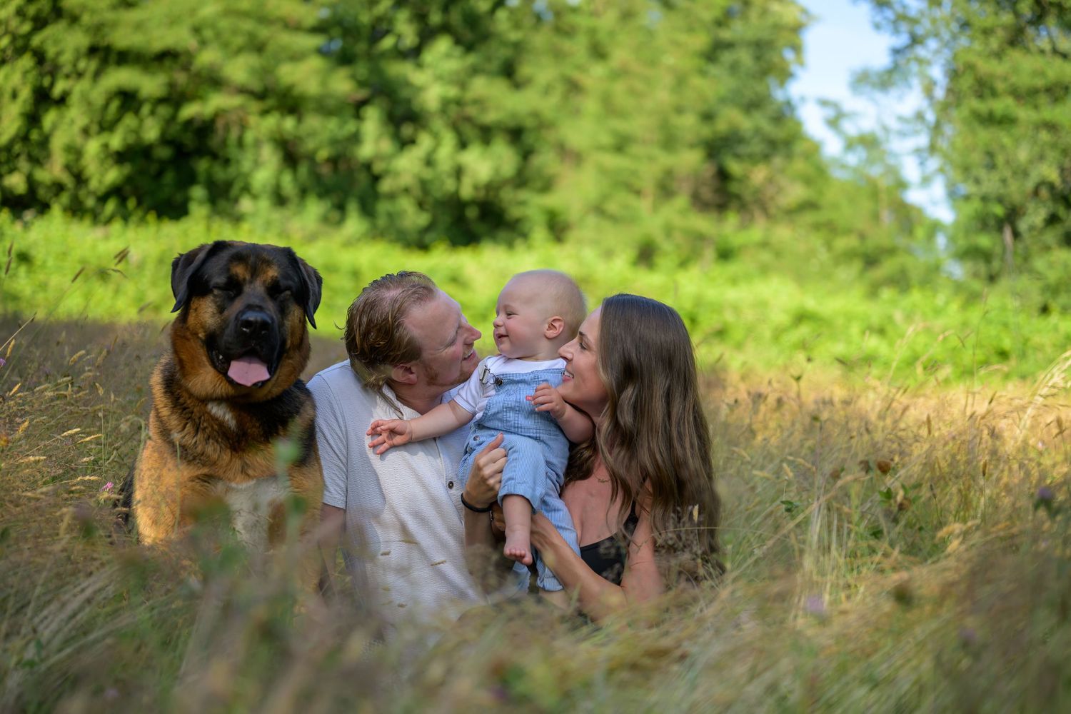 A heartwarming family portrait session in Deer Lake Park, Burnaby with tall grass and natural greenery in the background.