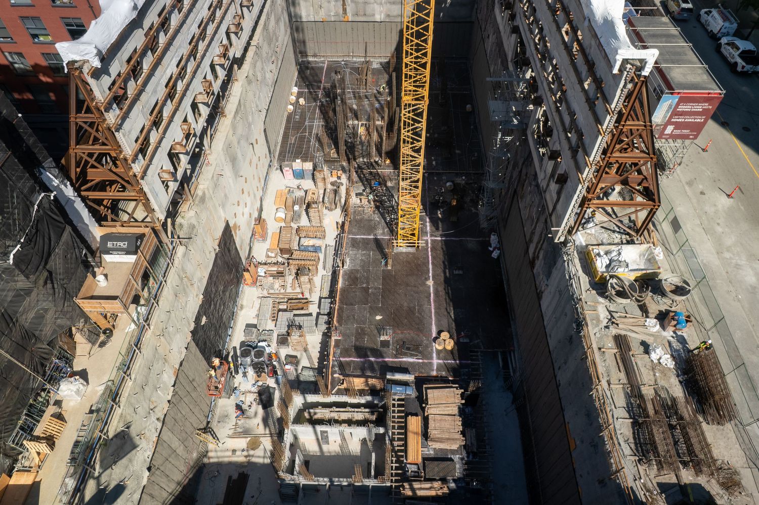 Aerial view of an urban construction site with exposed steel framework and equipment.
