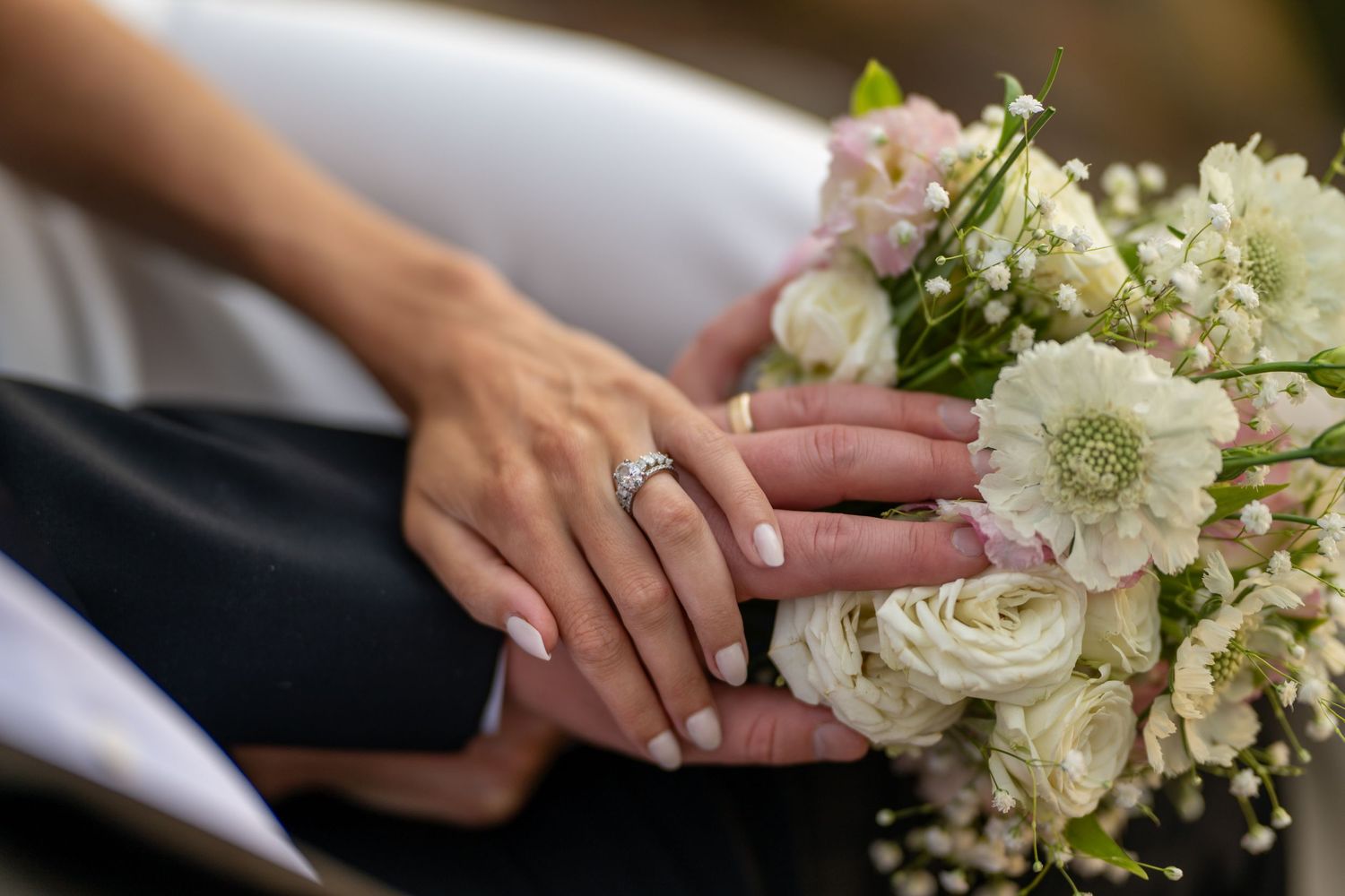 Close-up details of a white wedding bouquet with roses and baby's breath flowers.