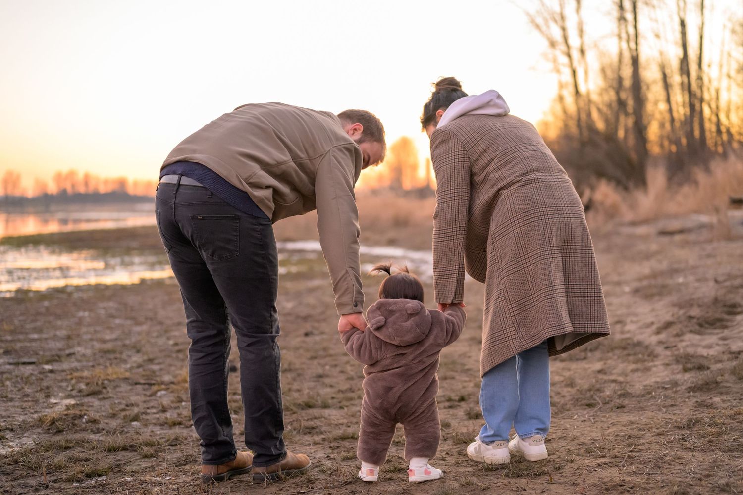Family with young child walking on a beach in Port Coquitlam during sunset