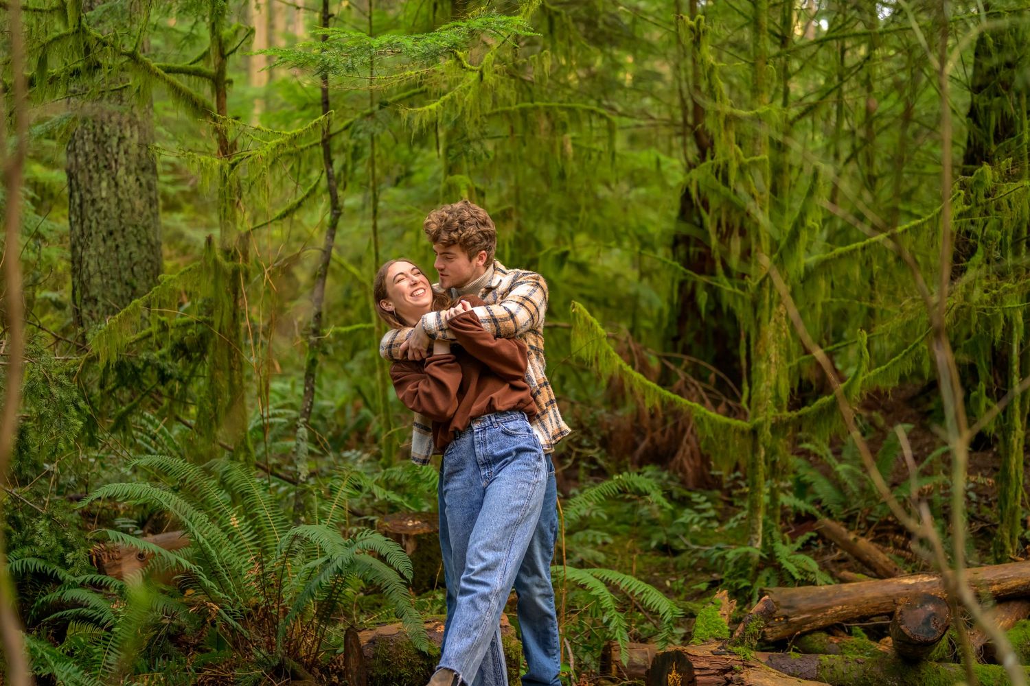 Couple sharing romantic moments in a lush green forest setting.