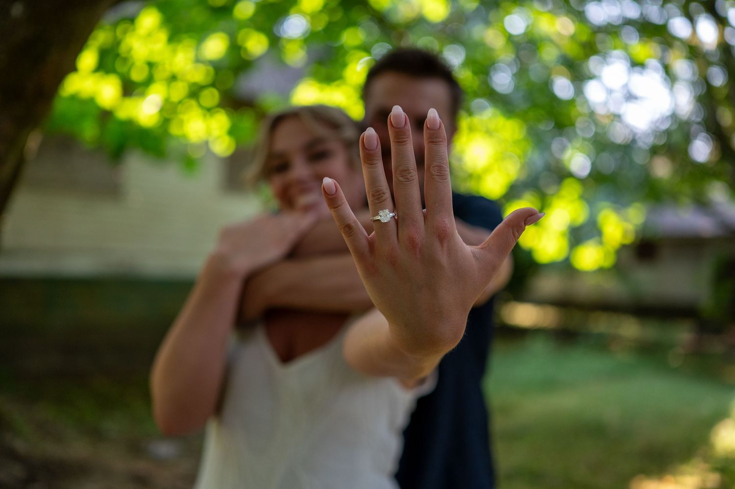 Joyful outdoor photoshoot with bright sunlit foliage in the background.