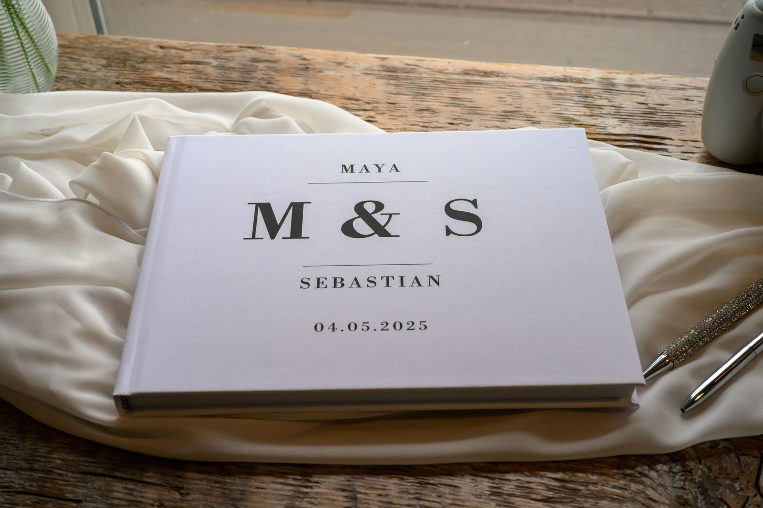 Wedding stationery with M & S monogram and names Maya and Sebastian displayed on silk fabric.