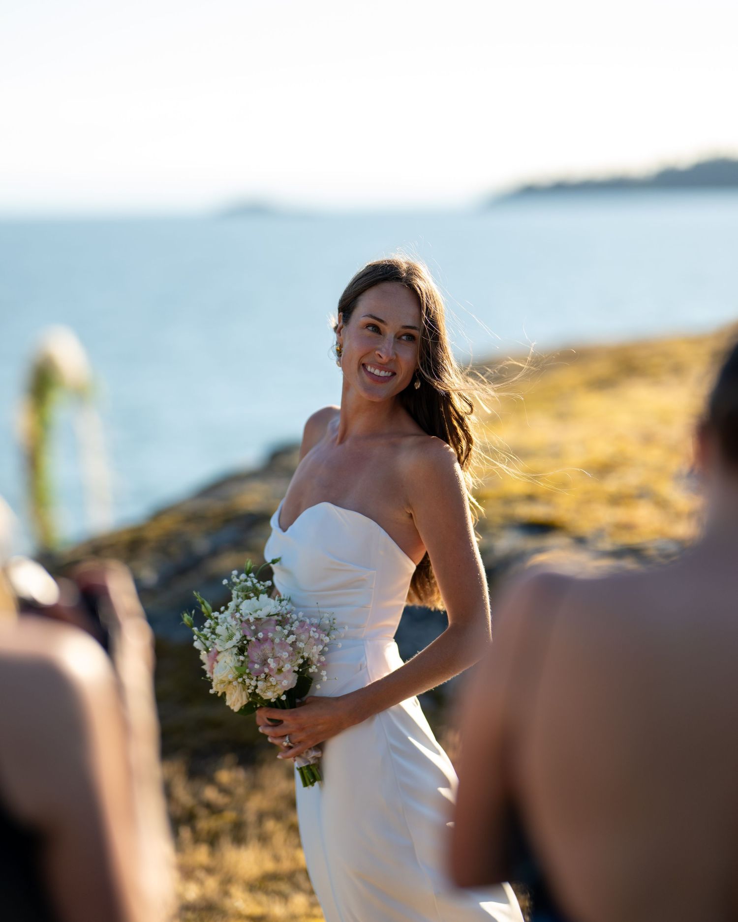 Wedding ceremony takes place on scenic coastal cliffside with ocean views.