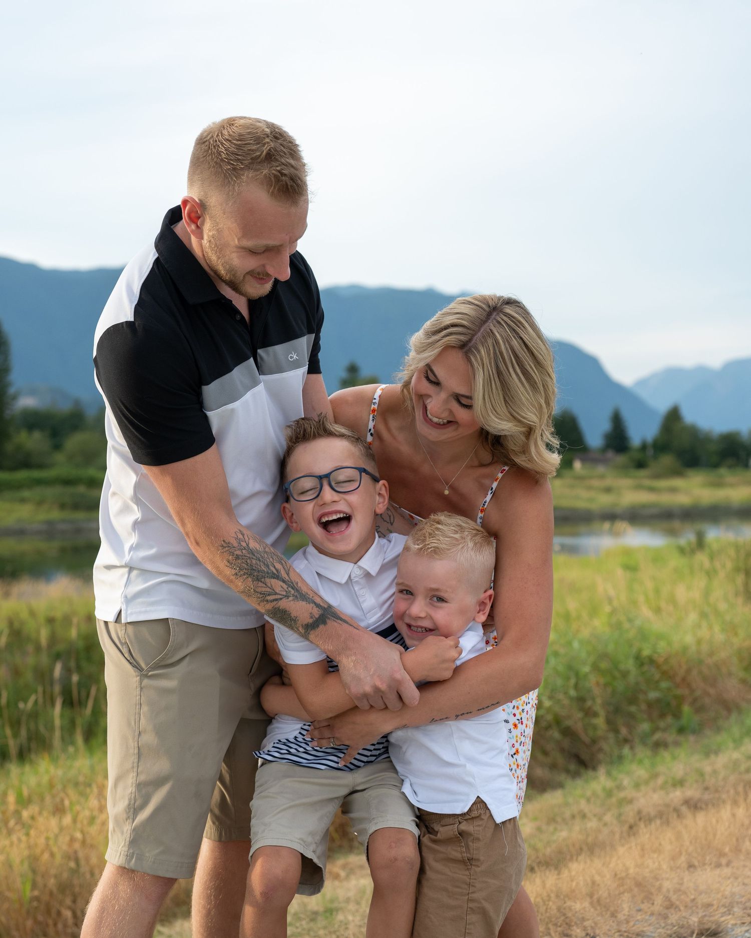 Playful family moment captured in an outdoor field with mountains in background.