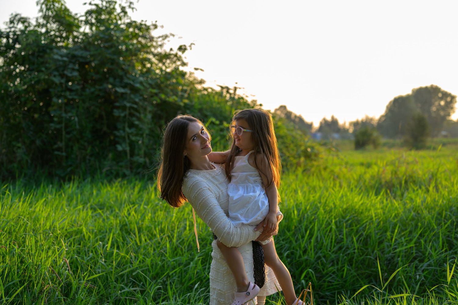 Family enjoying quality time in a lush green meadow at sunset.