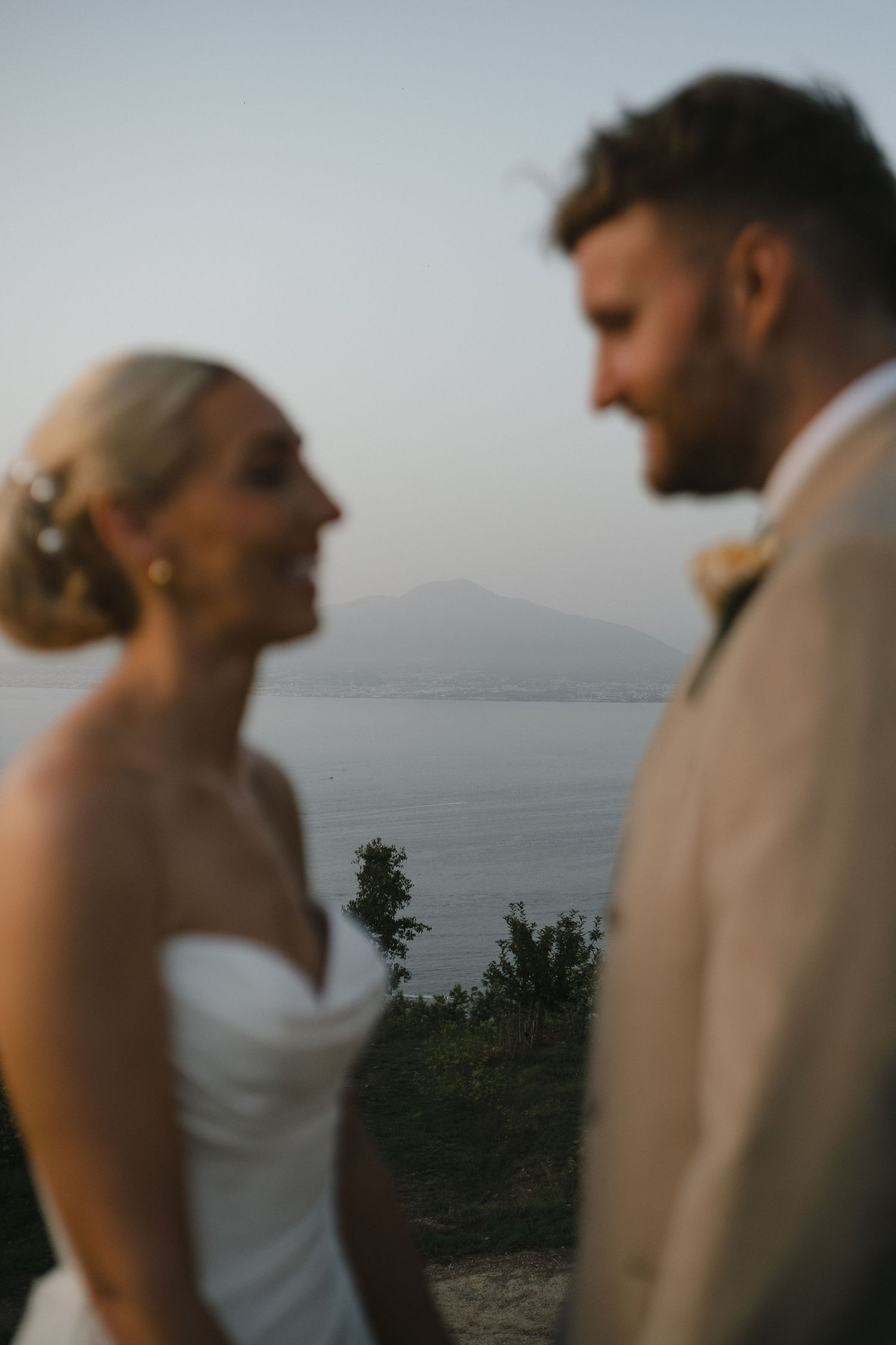 Bride and groom sharing a romantic moment with scenic lake and mountain backdrop.