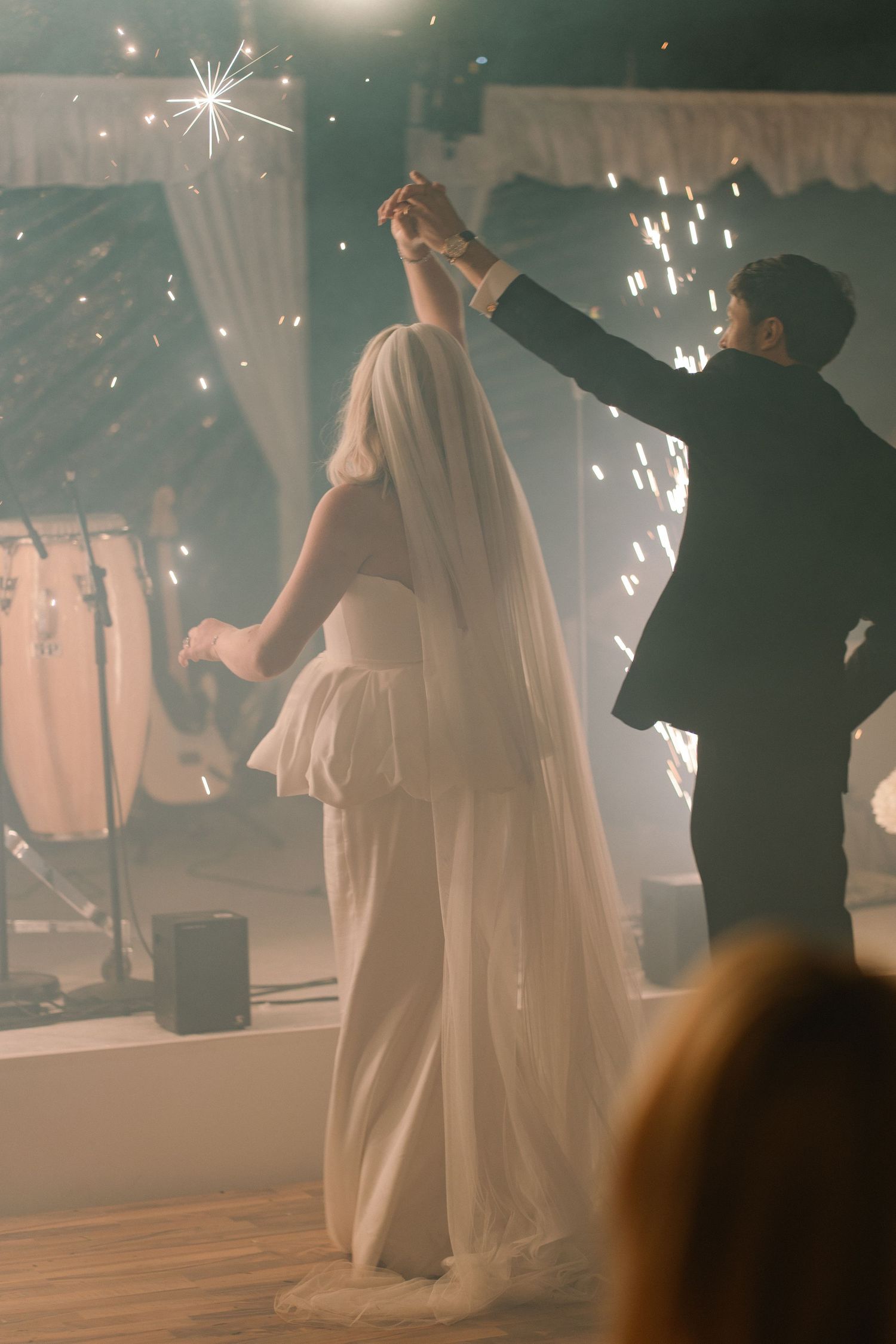 Bride and groom dancing their first dance with sparklers at a romantic wedding reception.