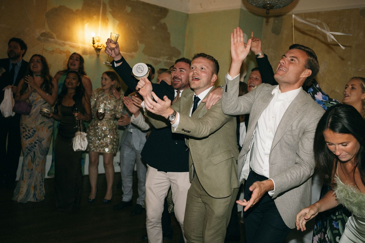 Guests dancing and celebrating at a wedding reception in an elegant venue with warm lighting.