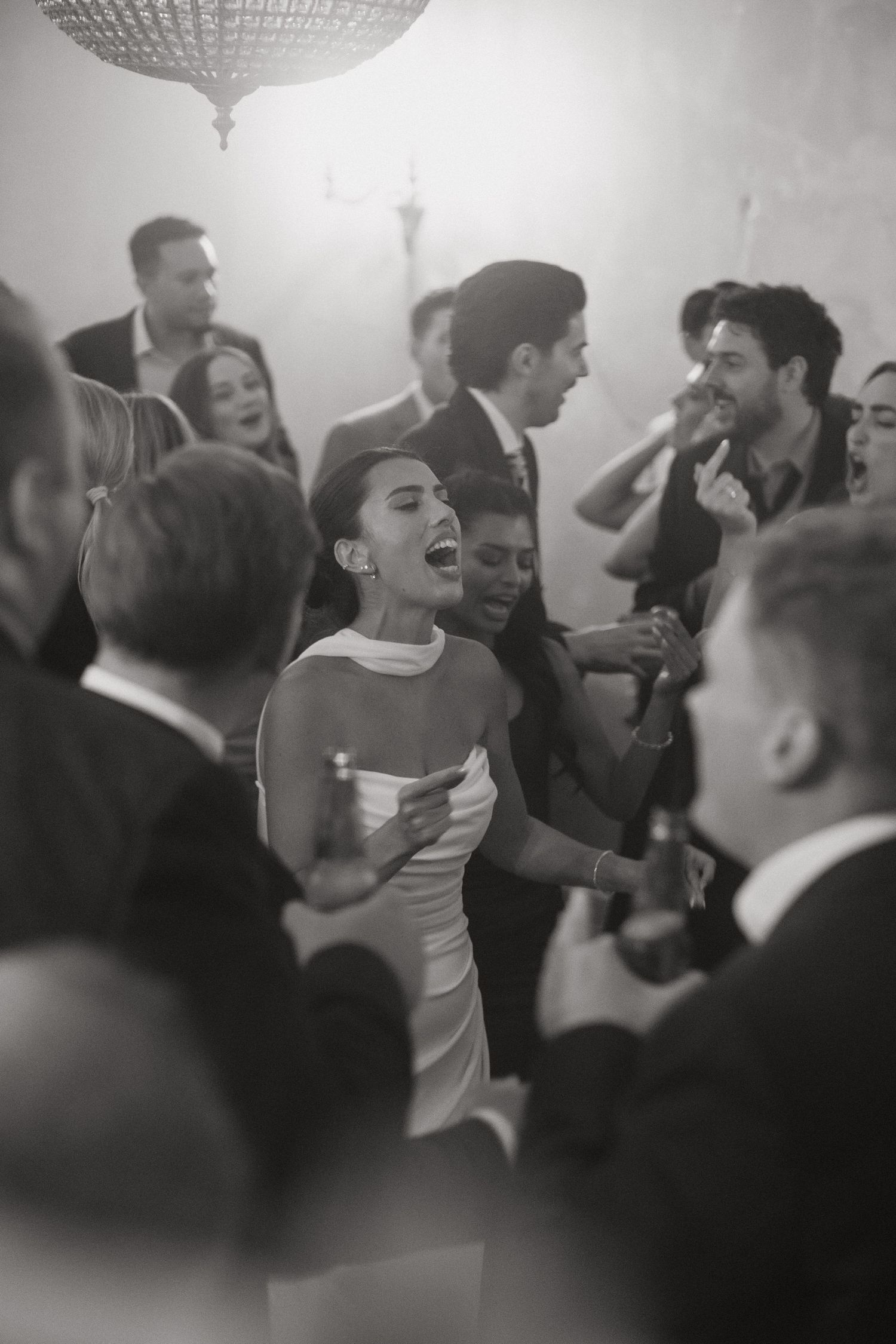 Black and white photo of guests dancing joyfully at an elegant wedding reception party.