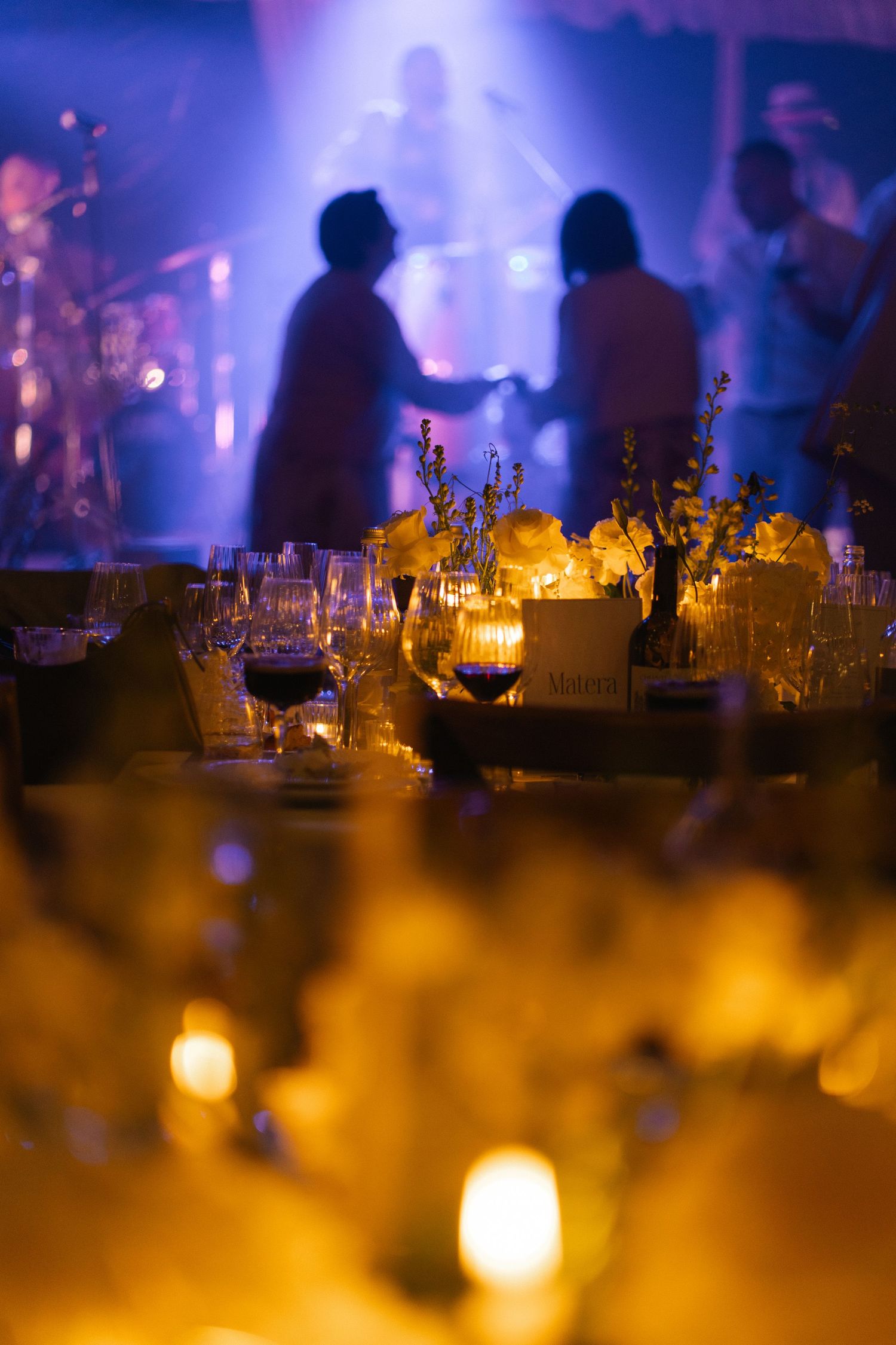Elegant wedding reception venue with candlelit tables and live band performing on stage.