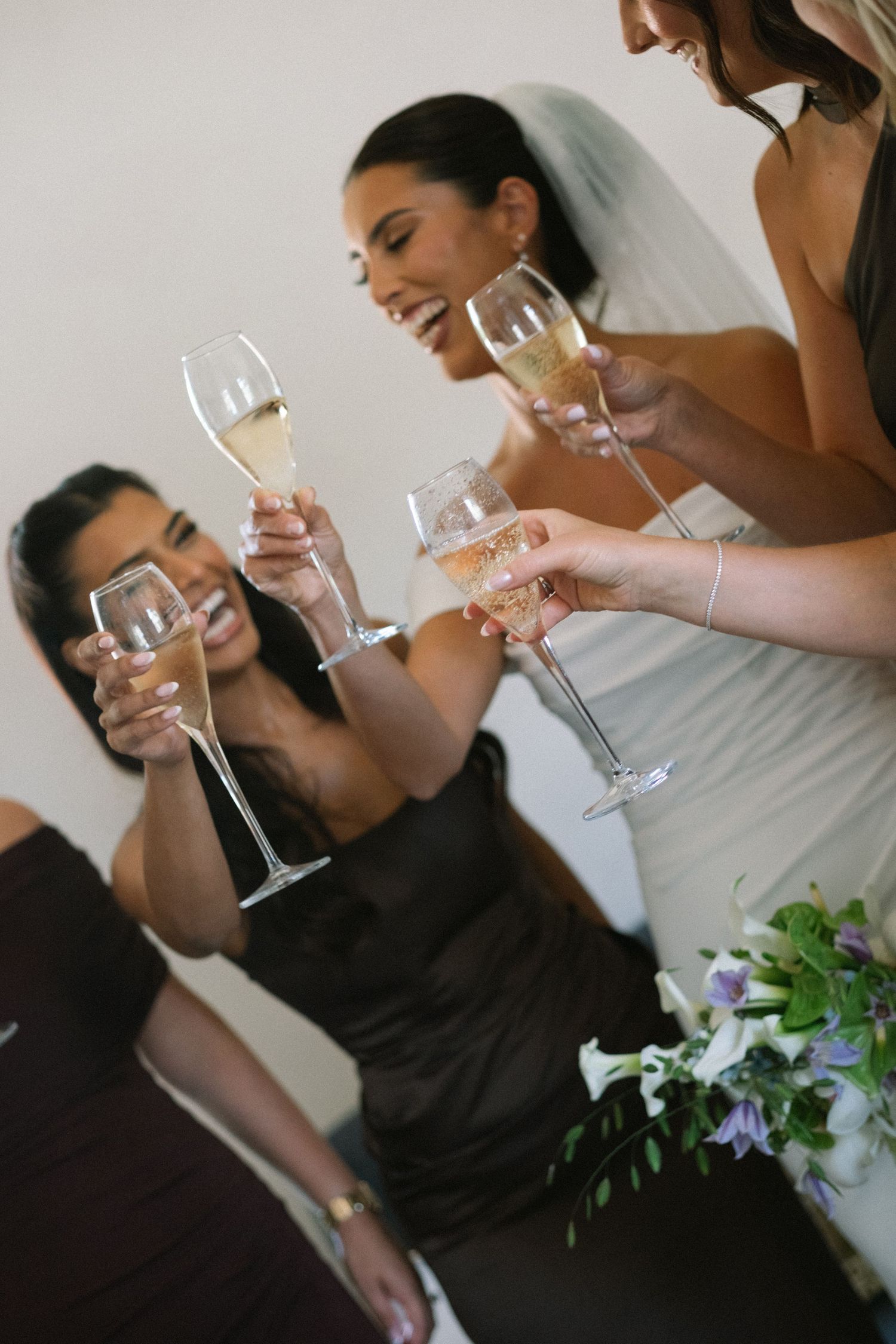Bride and bridesmaids toasting with champagne glasses at a wedding celebration.